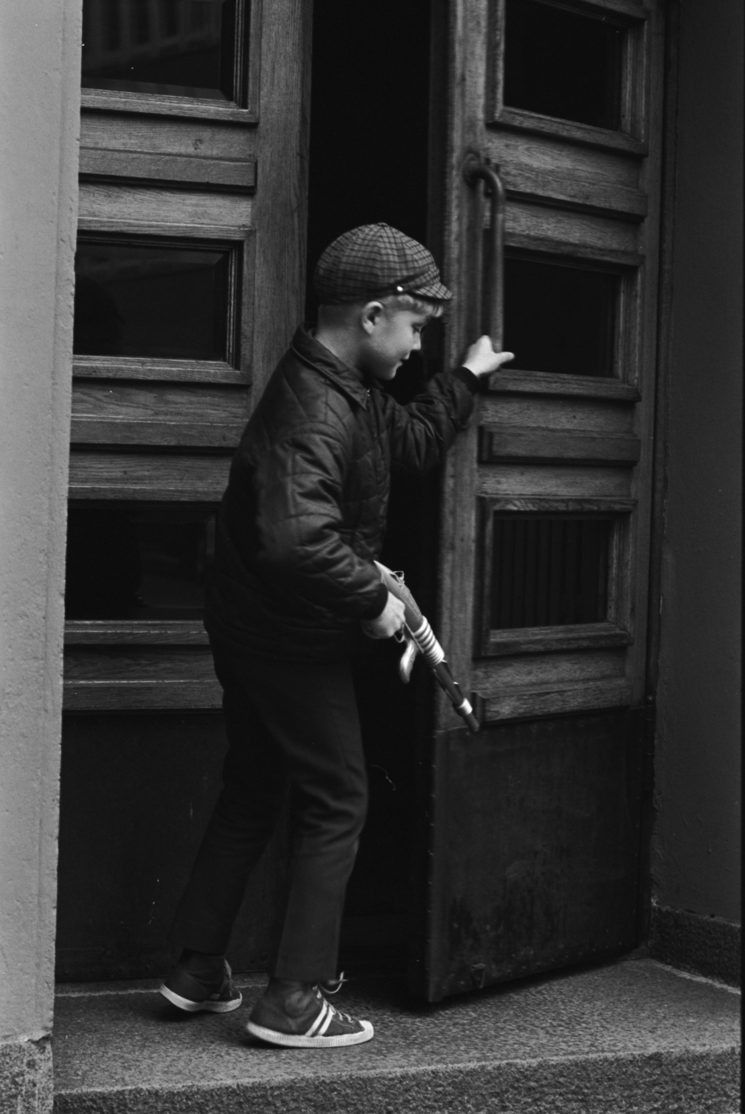 Kruununhaka, Meritullinkatu 13. Poika leikkiaseen kanssa menossa Meritullinkatu 13:n ulko-ovesta sisälle.