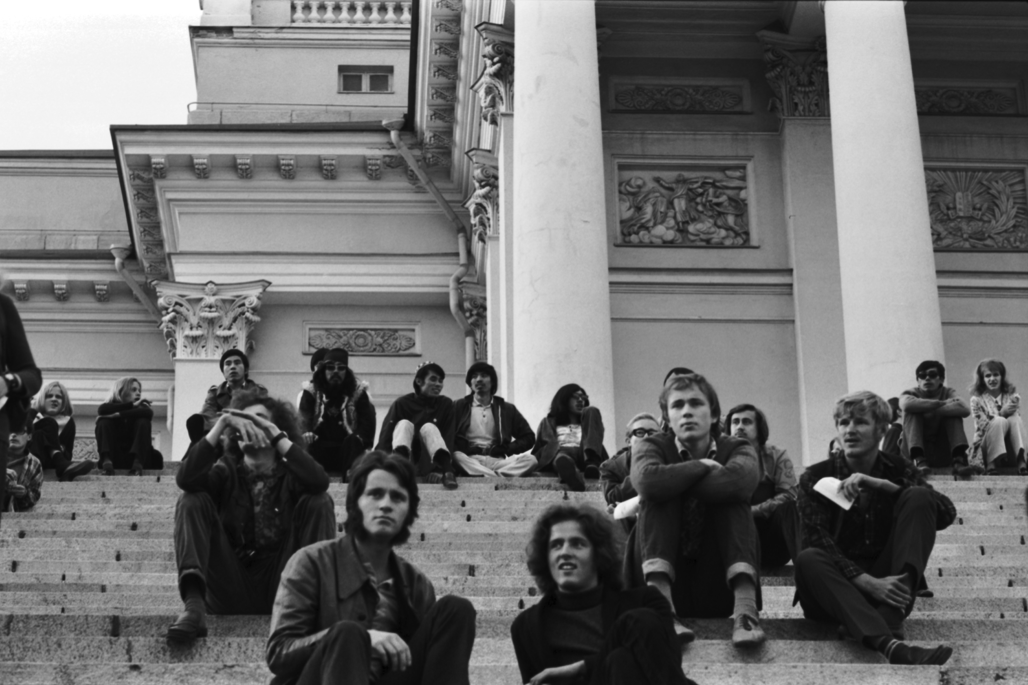 Hallituskatu 7. Ihmisiä istumassa Tuomiokirkon portailla.