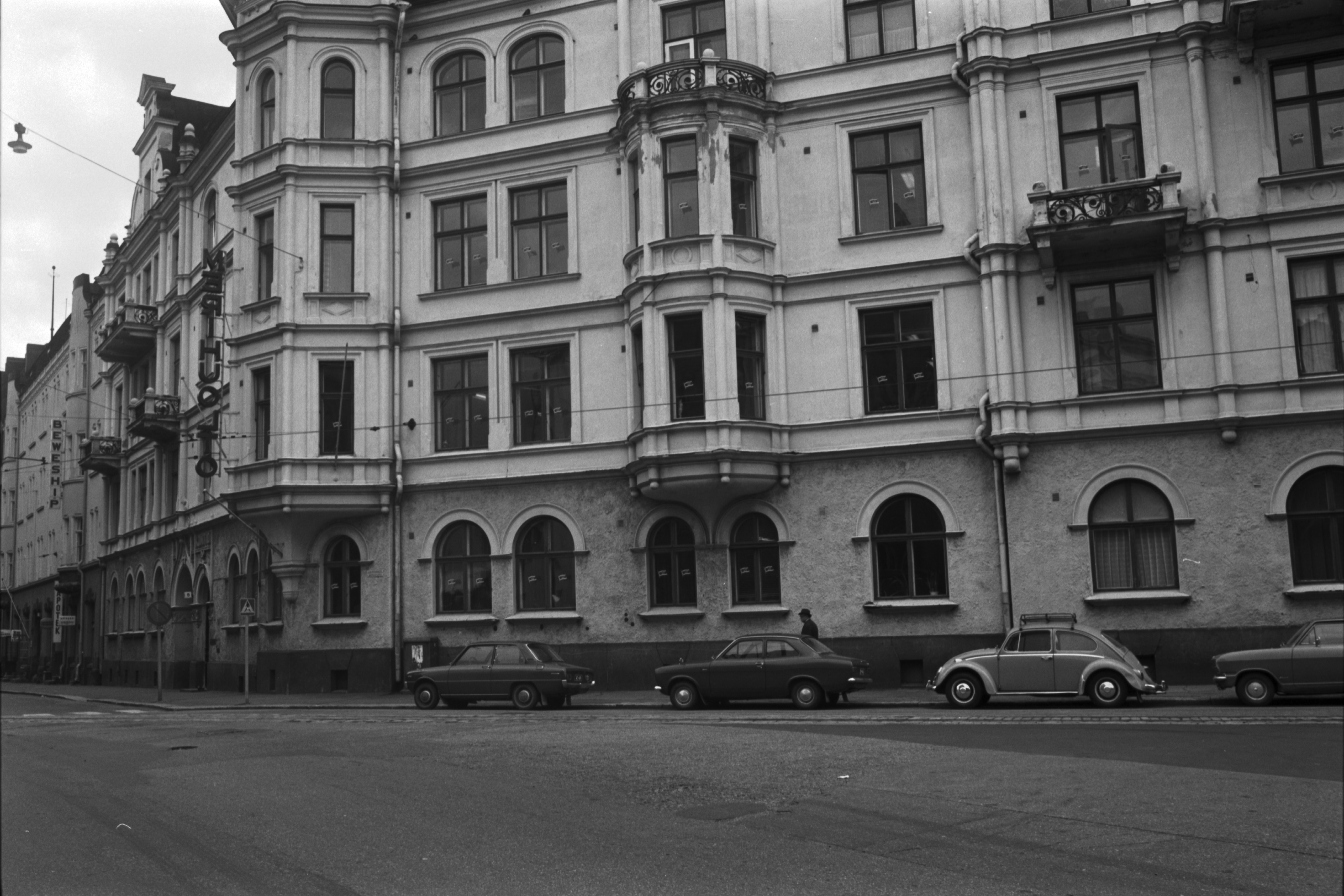 Kauppiaankatu 1-3. Kruunuvuorenkatu 5. Kruunuvuorenkadun ja Kauppiaankadun kulmatalon Kruunuvuorenkadun puoleista julkisivua. Rakennuksessa on Merihuolto Oy:n konttori ja julkisivussa sen valomainos. Vasemmassa reunassa Kruunuvuorenkatu 3, jossa huolintaliike Beweshipin konttori ja valomainos.