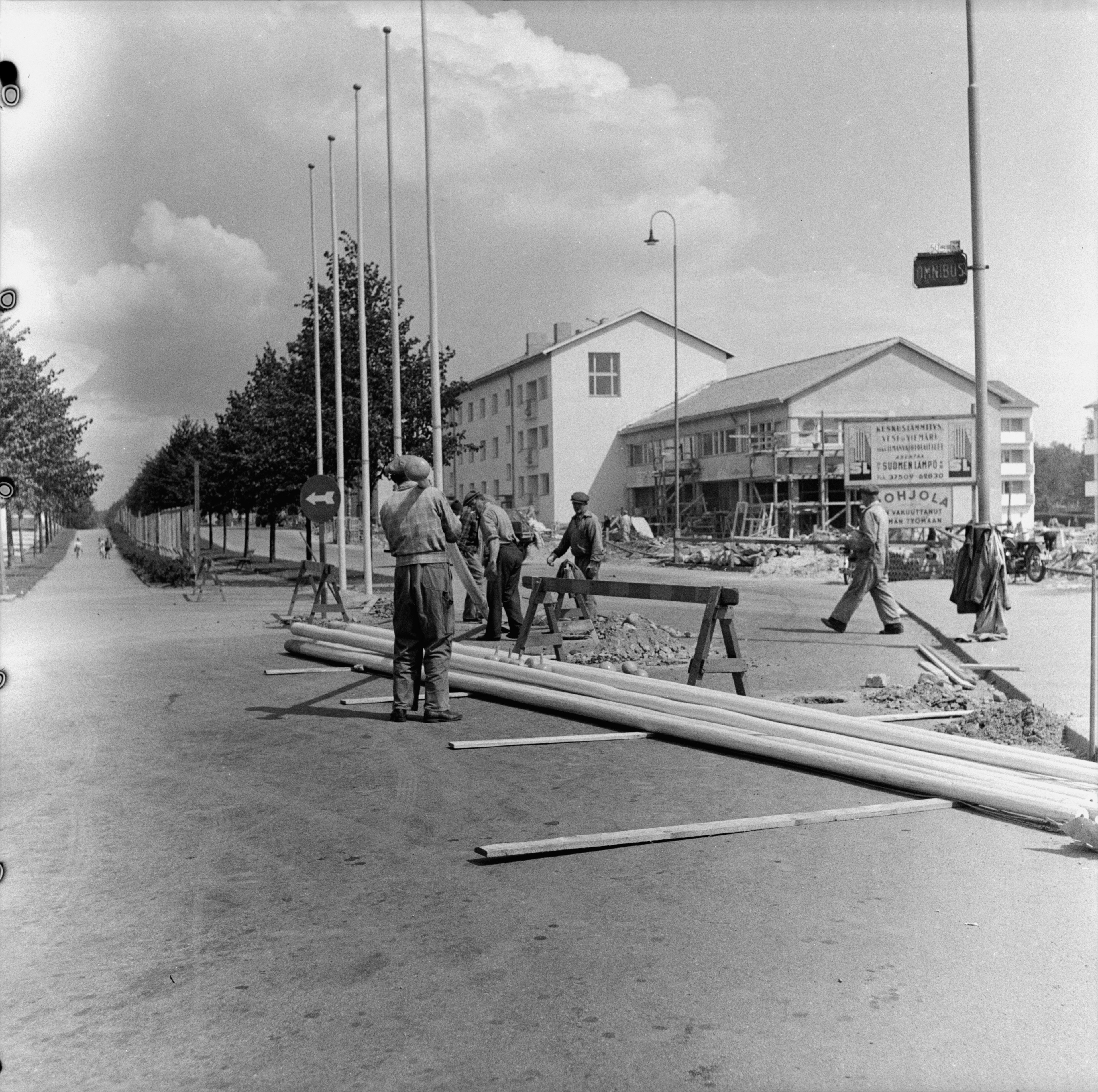 Helsingin olympialaiset 1952. Lipputankojen pystytys Käpylän Kisakylän portilla.Taustalla Koskelantie 7-9.