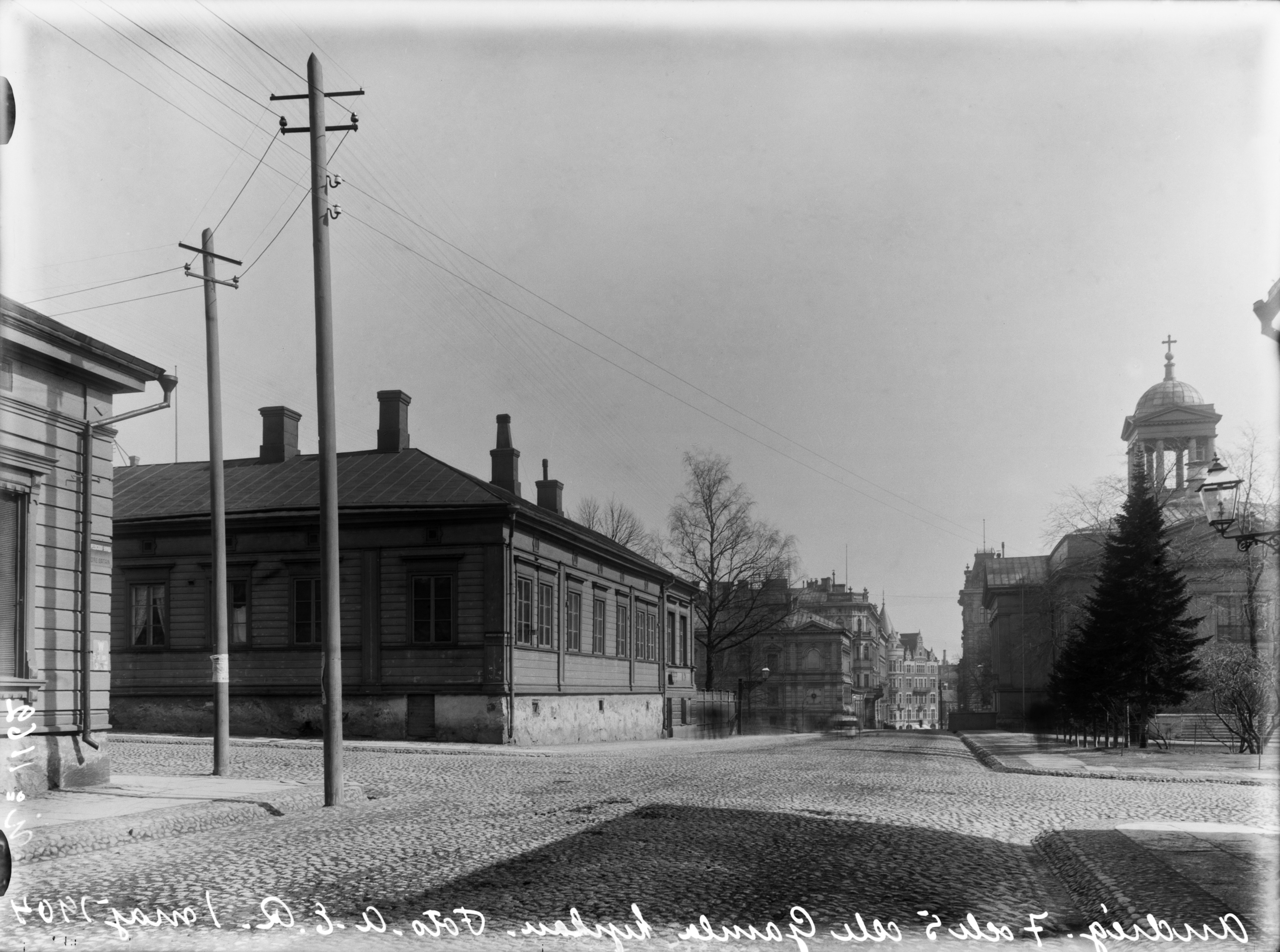 Näkymä Antinkatua (=Lönnrotinkatu) pitkin itään, vasemmalla nro:t  7 (=Annankatu 19) ja 5, oikealla nro 6, Vanha kirkko.