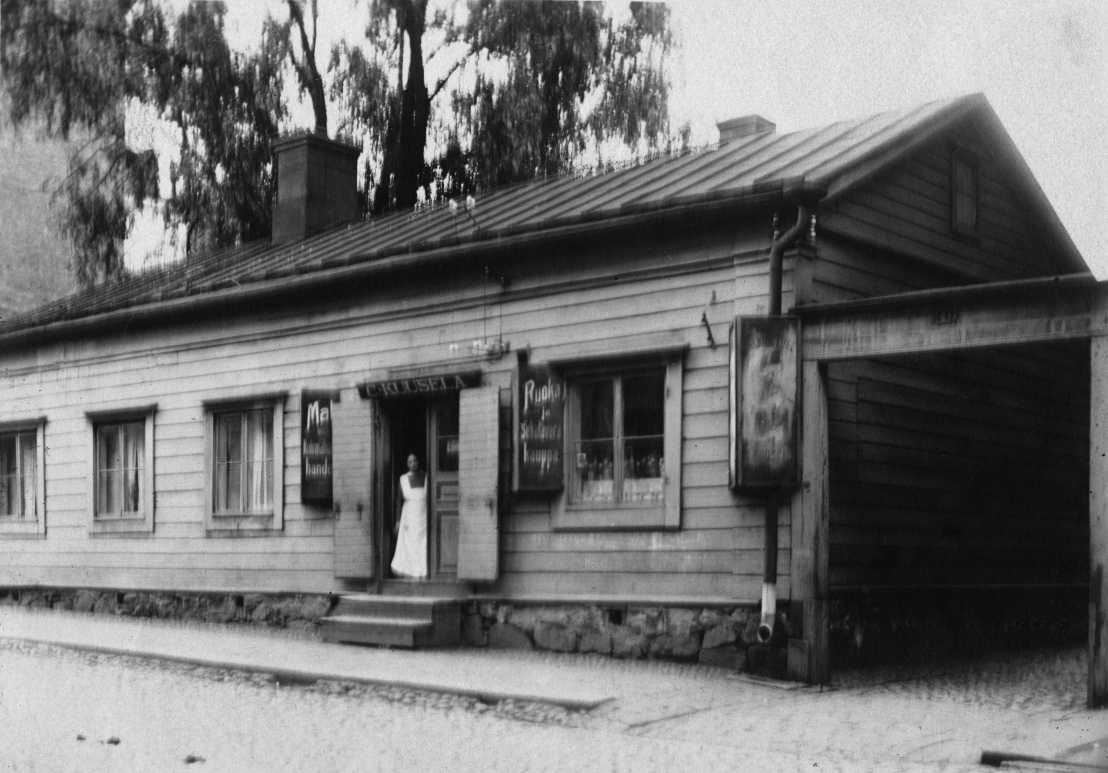 Kauppias Charlotta Kuusela (s.1871, o.s. Peltonen) ruoka- ja sekatavarakauppansa C. Kuuselan edustalla Uudenmaankatu 26:ssa. Perheen koti sijaitsi samassa talossa.
