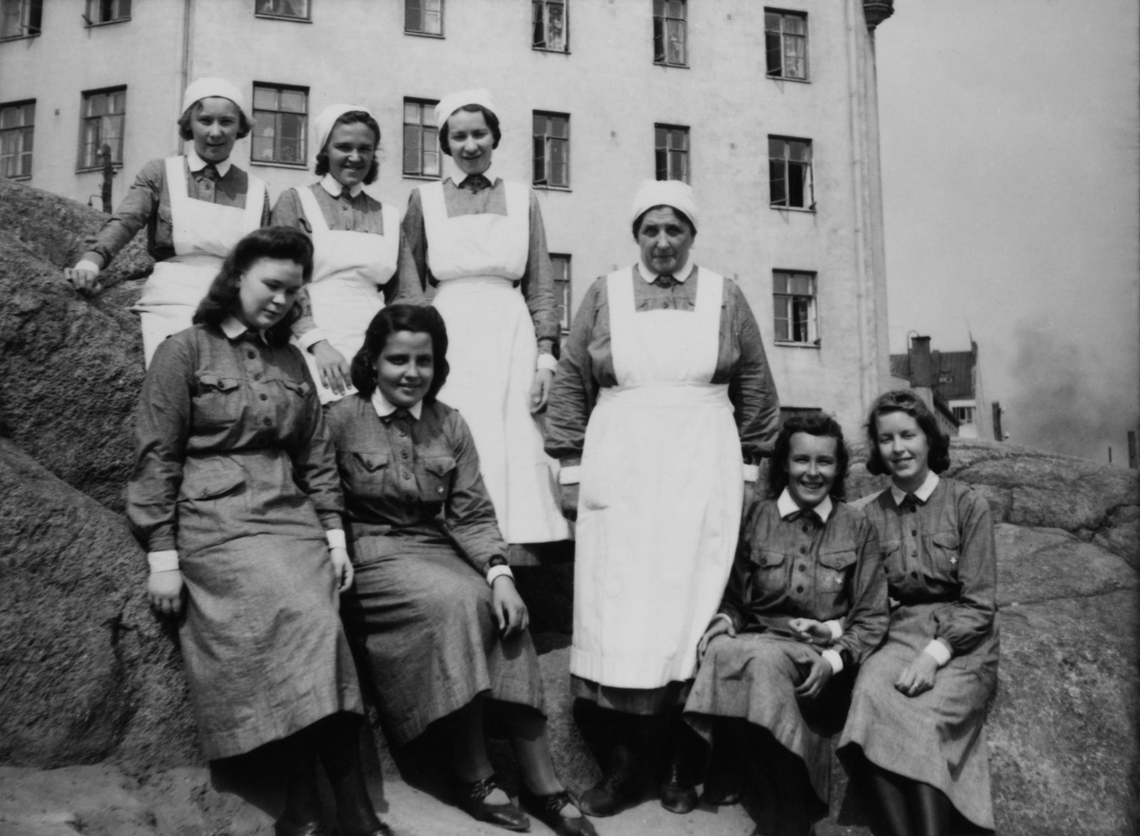 Lottia ryhmäkuvassa Katri Valan puiston kallioilla. Taustalla on Vilhonvuorenkuja 20.