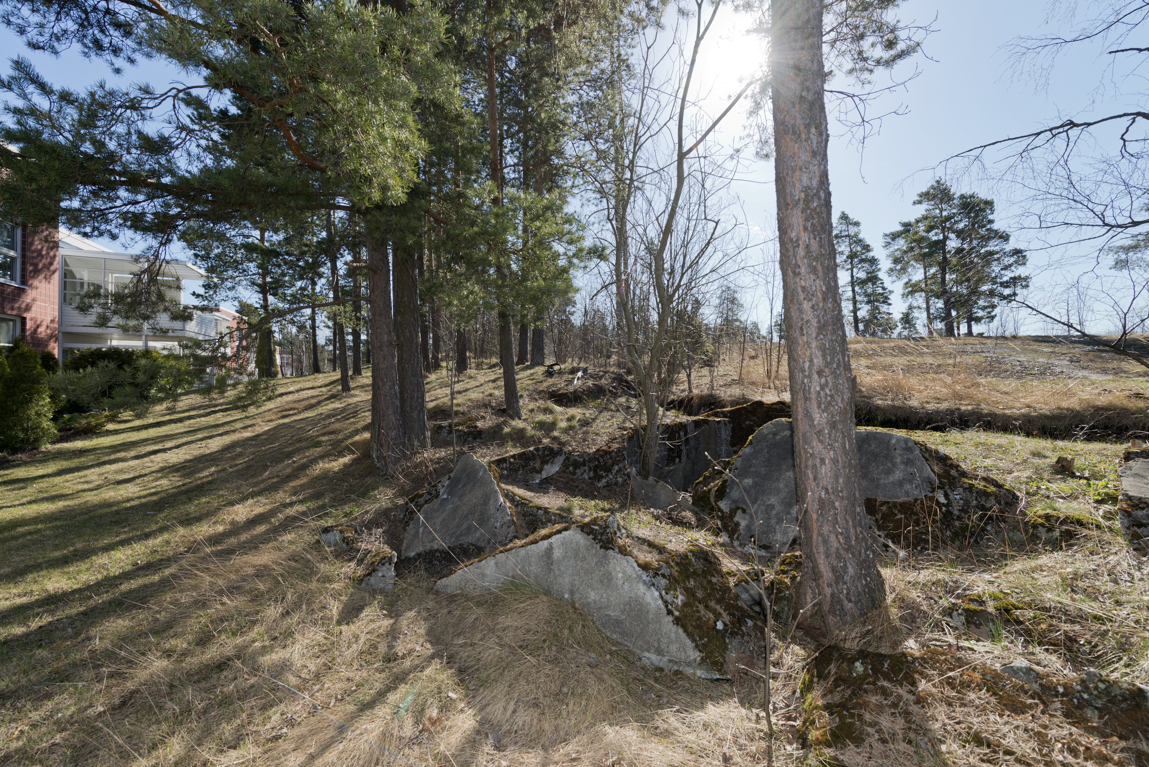 Länsimäki. Ensimmäisen maailmansodan aikainen maalinnoitus, puolustusasema II:8 Länsimäessä, Vantaalla. Kuvassa näkyy kallioon louhittua, betonilla tuettua taisteluhautaa sekä konekivääriasema aseman pohjoisosassa. Betonista rakennetun nelikulmaisen aseman seinässä näkyy komero konekiväärin jäähdytysvesisäiliötä varten. Katto on räjäytetty. Aseman sisällä ja ampumasektorissa lojuu kookkaita betonilohkareita. Taustalla vasemmalla on asuinrakennuksia. Kuvaussuuntana itä-kaakko.