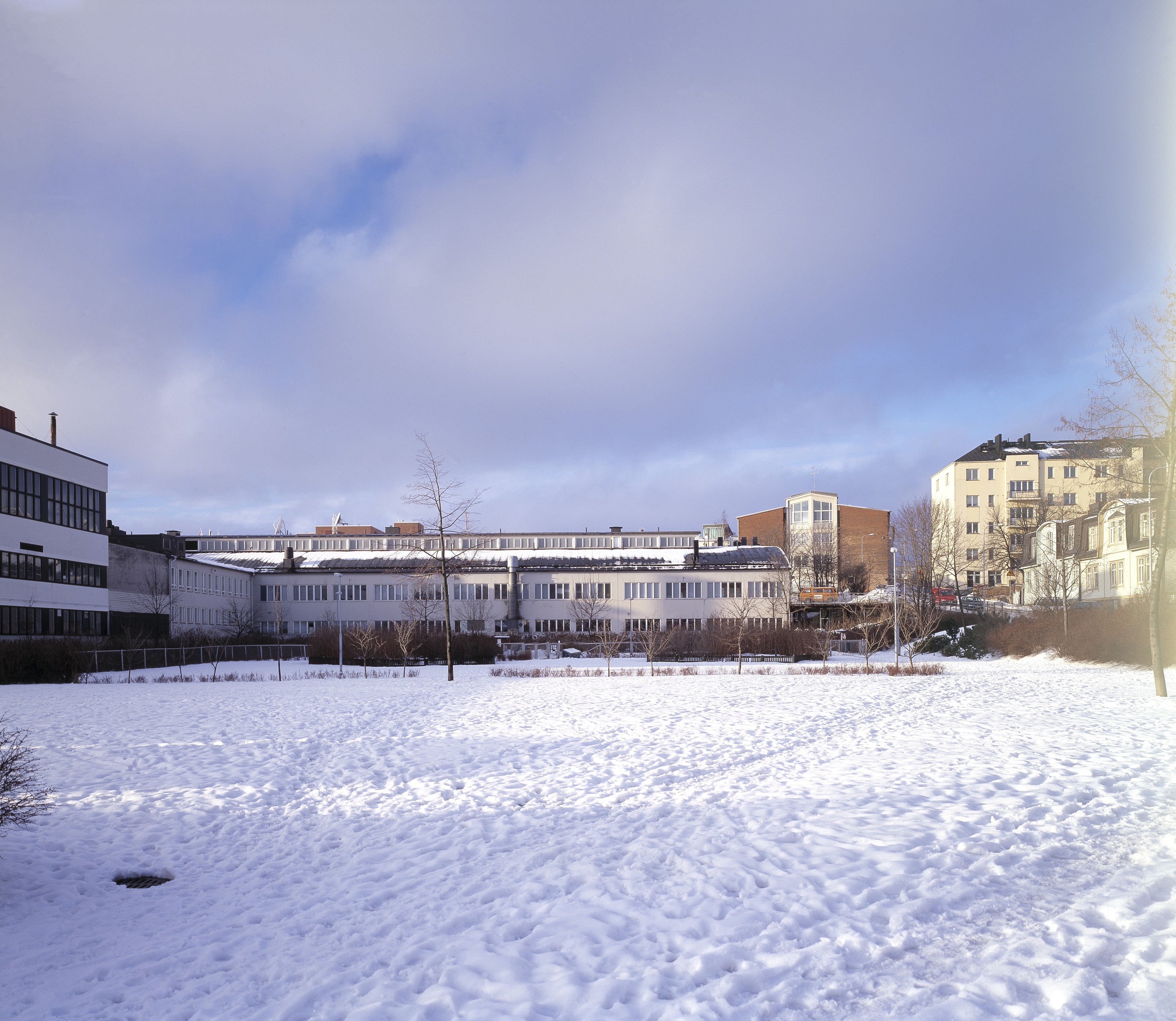 Posti ja Tele Sturenkatu 21. Rakennus alunperin osa Oy Volvo Ab:n pääkonttoria. Kiinteistössä oli myös Volvon huolto- ja peltikorjaamo, uusien autojen myyntipiste sekä varaosien ja tarvikkeiden myynti. Kuvassa olevassa hallissa oli uusien autojen näyttelytila. Rakennusta laajennettiin arkkitehti Ole Gripenbergin suunnitelmien mukaan vuonna 1942. Uusia tiloja olivat katettu paikoitustila, luentosali, konttori ja korjaamon laajennus. Kaarihallia pidennettiin Arthur Rosendahlin suunnitelmien mukaan vuonna 1945. Kaarihallin päätyyn lisättiin ajosillat P. G. Gyldénin suunnitelmien mukaan vuonna 1955. Katettu paikoitustila muutettiin sisätilaksi ja samalla tehtiin joitakin muutoksia konttori- ja varastotiloissa arkkitehti Bertel Gripenbergin suunnitelmien mukaan vuonna 1958. Bertel Gripenberg suunnitteli rakennukseen muitakin muutoksia 1960 -luvulla ja 1970 -luvulla. Ikkuna- ja ovimuutoksia sekä käyttötarkoituksen vaihtumisesta on tehty myös 1980 -luvulla ja 1990 -luvulla.  Halliosan kaarevaa kattoa korostaa vielä koko hallin mittainen kattolyhty.