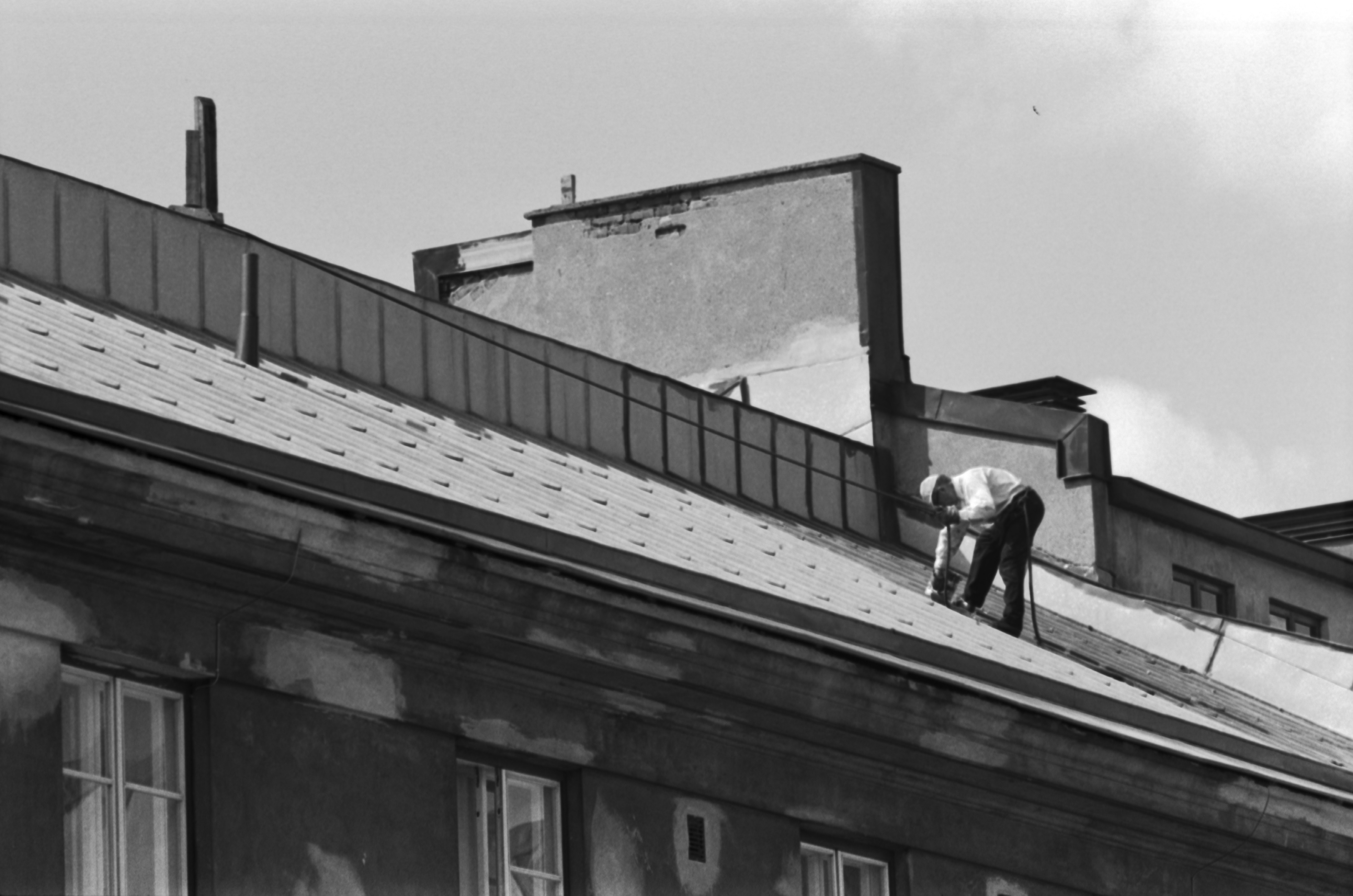 Mies maalaamassa Liisankatu 6:n kattoa.