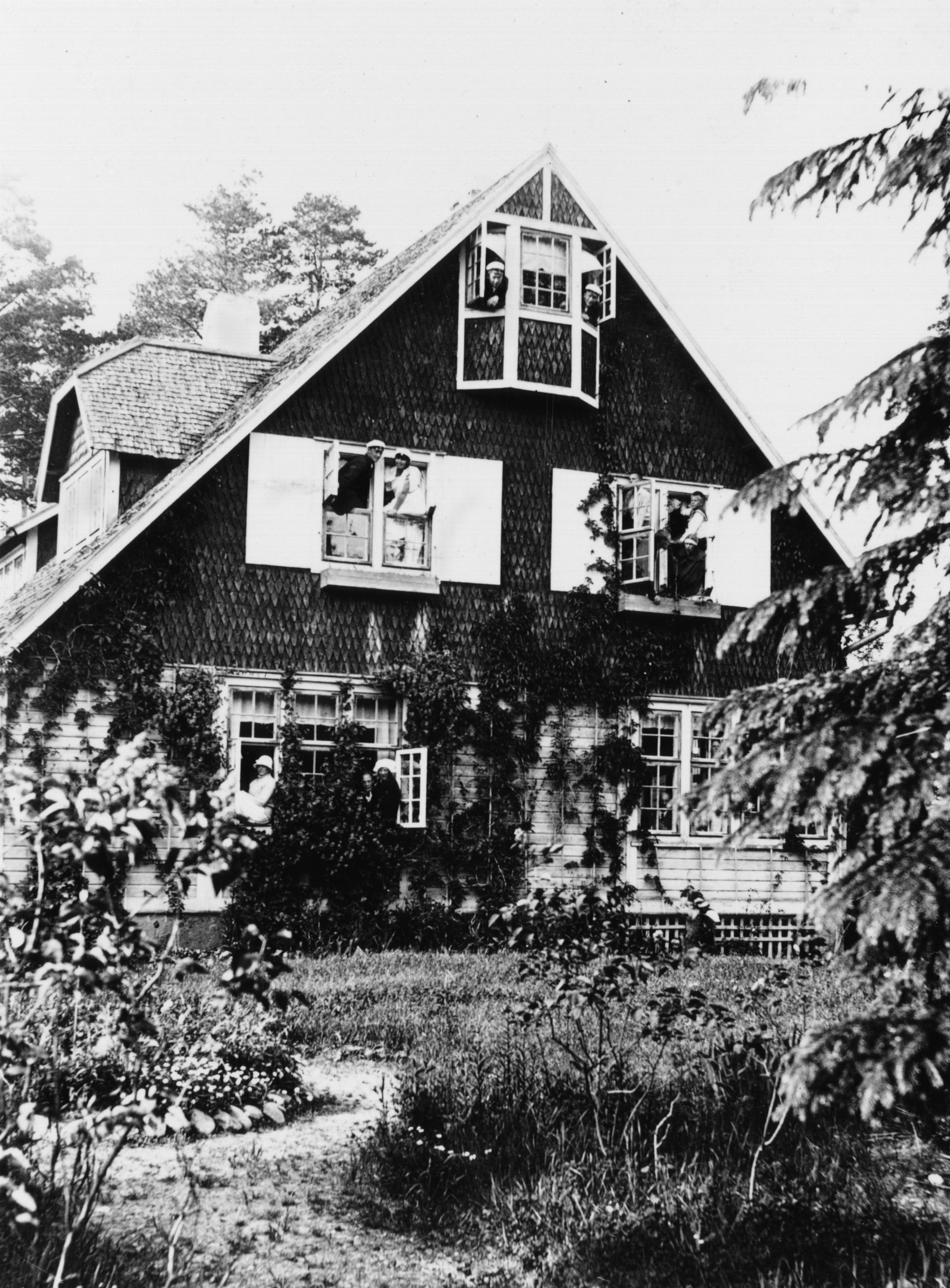 Ihmisiä kurkistelemassa ulos huvila Åsan ikkunoista juhannuksena 1924.