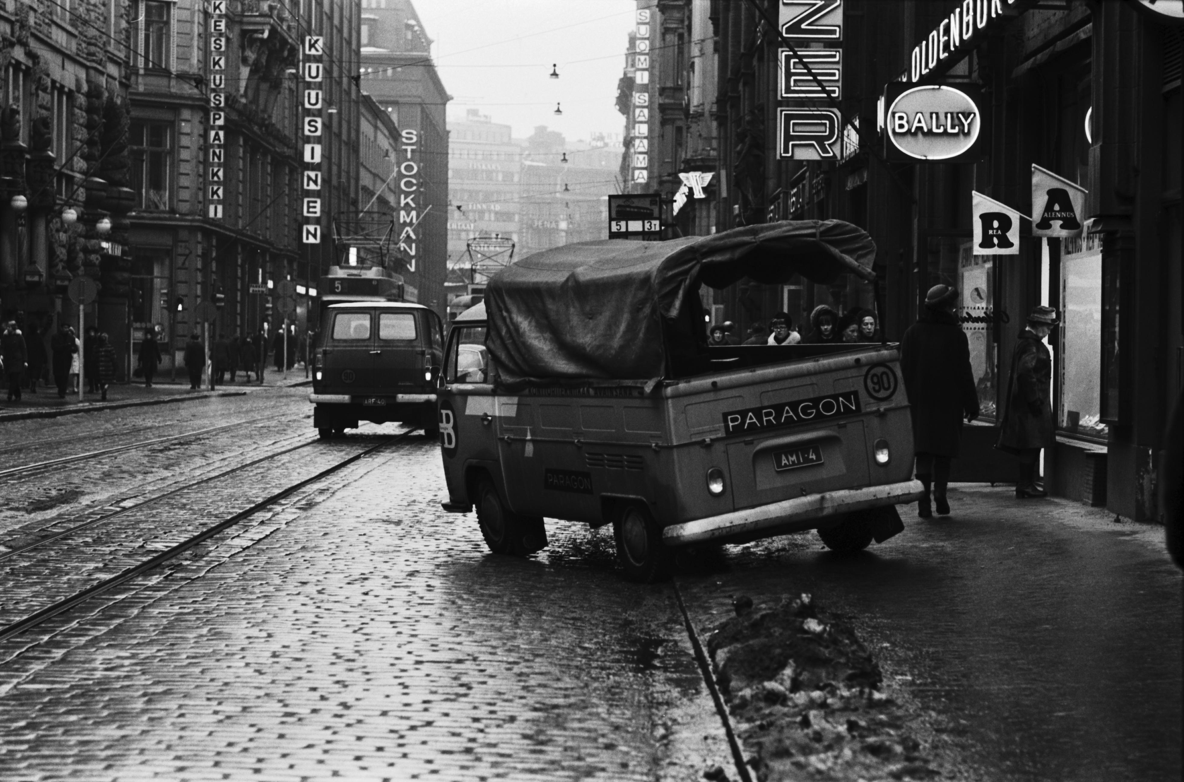 Kluuvi, Aleksanterinkatu. Kävelykatukokeilu (12.6.1970-8.1.1971) on päättynyt. Paragonin konttoritarvikeliikkeen VW-pakettiauto lähdössä jalkakäytävältä liikkeelle. Oikealla Musiikki-Fazerin ja Oldenburgin kenkäkaupan myymälät. Näkymä Kluuvikadun suunnalta Mannerheimintielle päin.