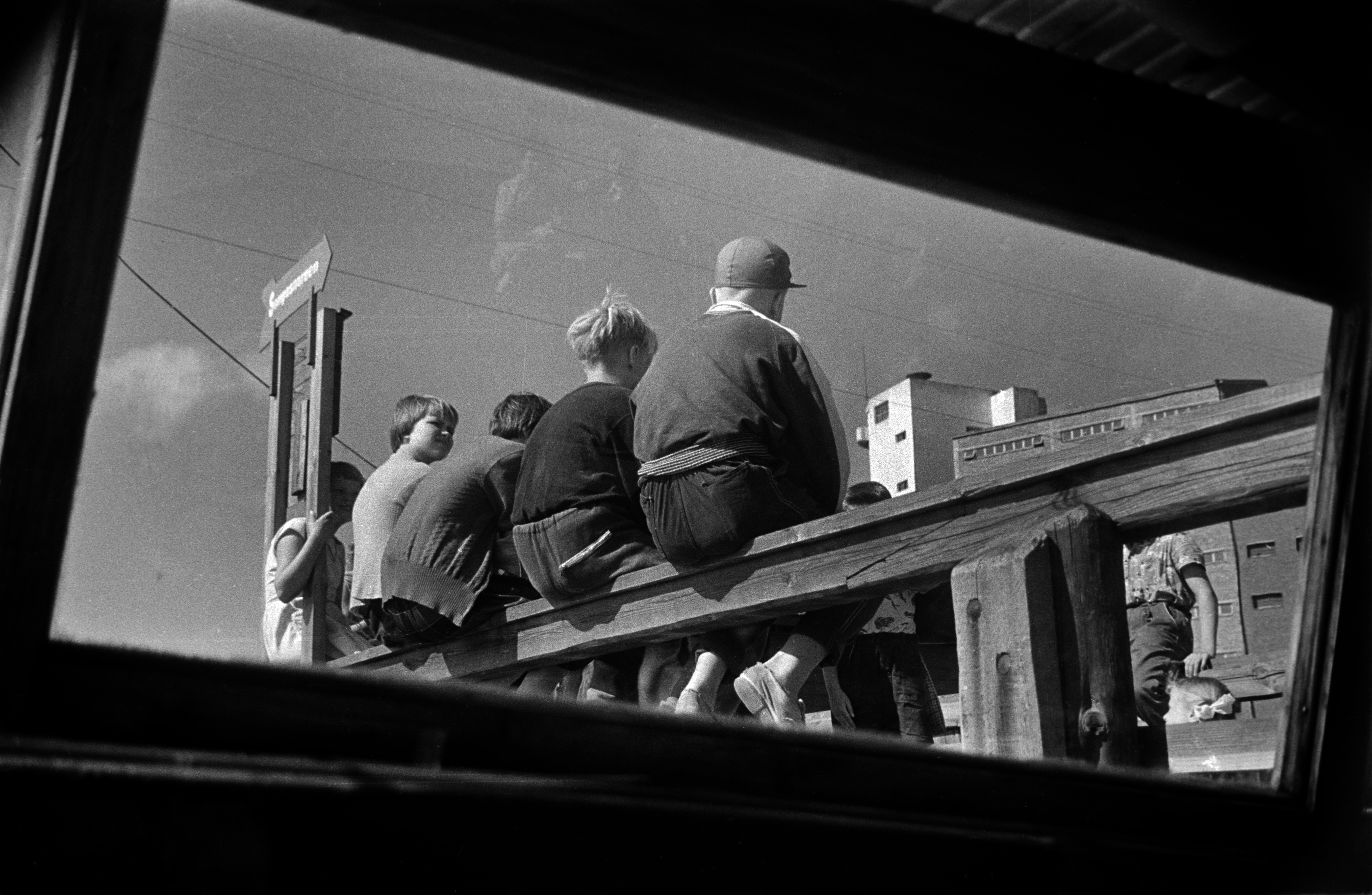 Lapsia istumassa Sörnäisissä Kaikukadun päässä sijainneen laiturin kaiteella. Laiturilta oli kuljetus Elannon työntekijöiden lasten kesäsiirtolaan Sompasaareen. Kuva otettu veneen ikkunasta.