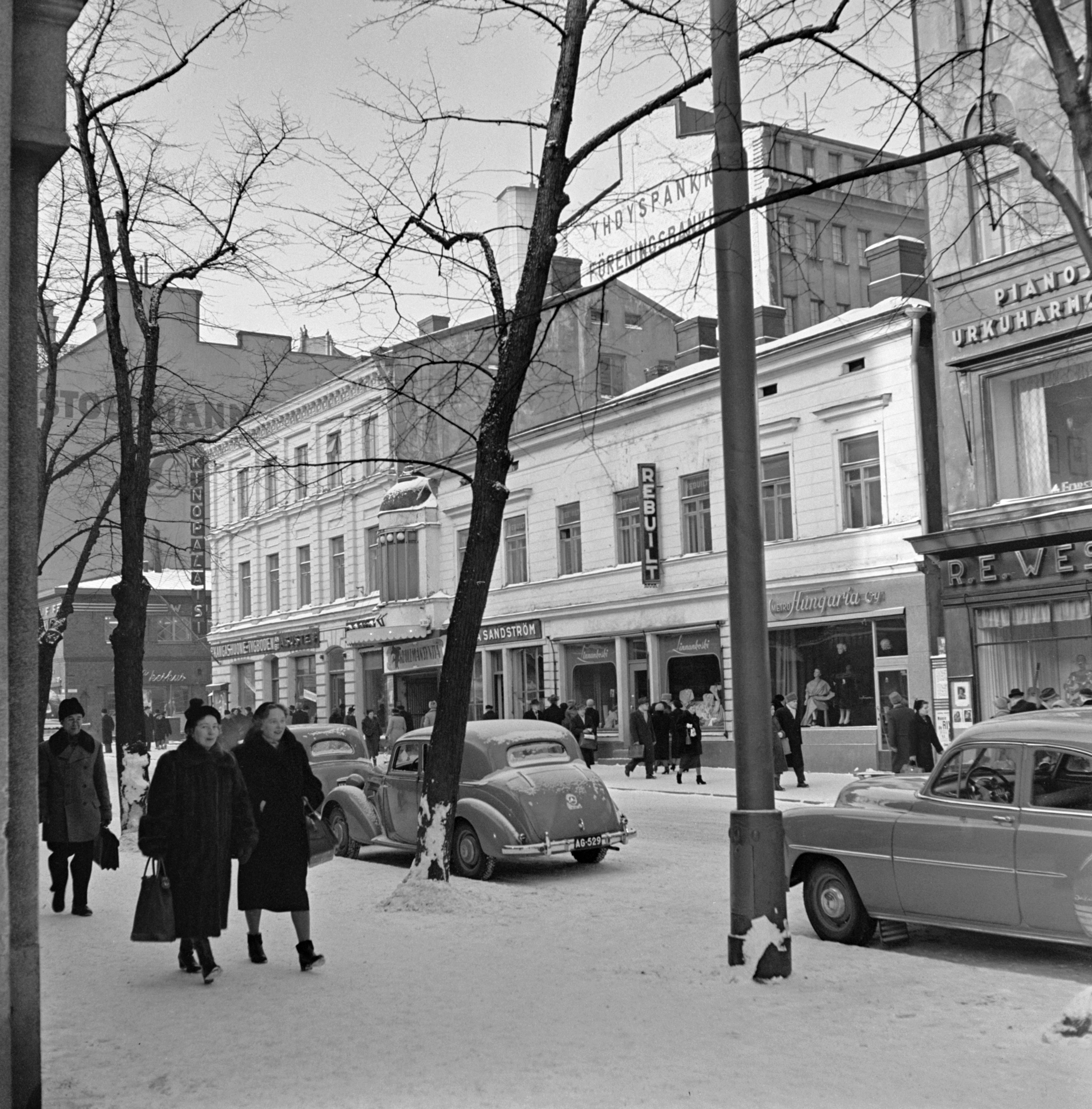 Jalankulkijoita ja autoja Pohjoisesplanadilla.Taustalla elokuvateatteri Kino-Palatsin talo, Pohjoisesplanadi 39.