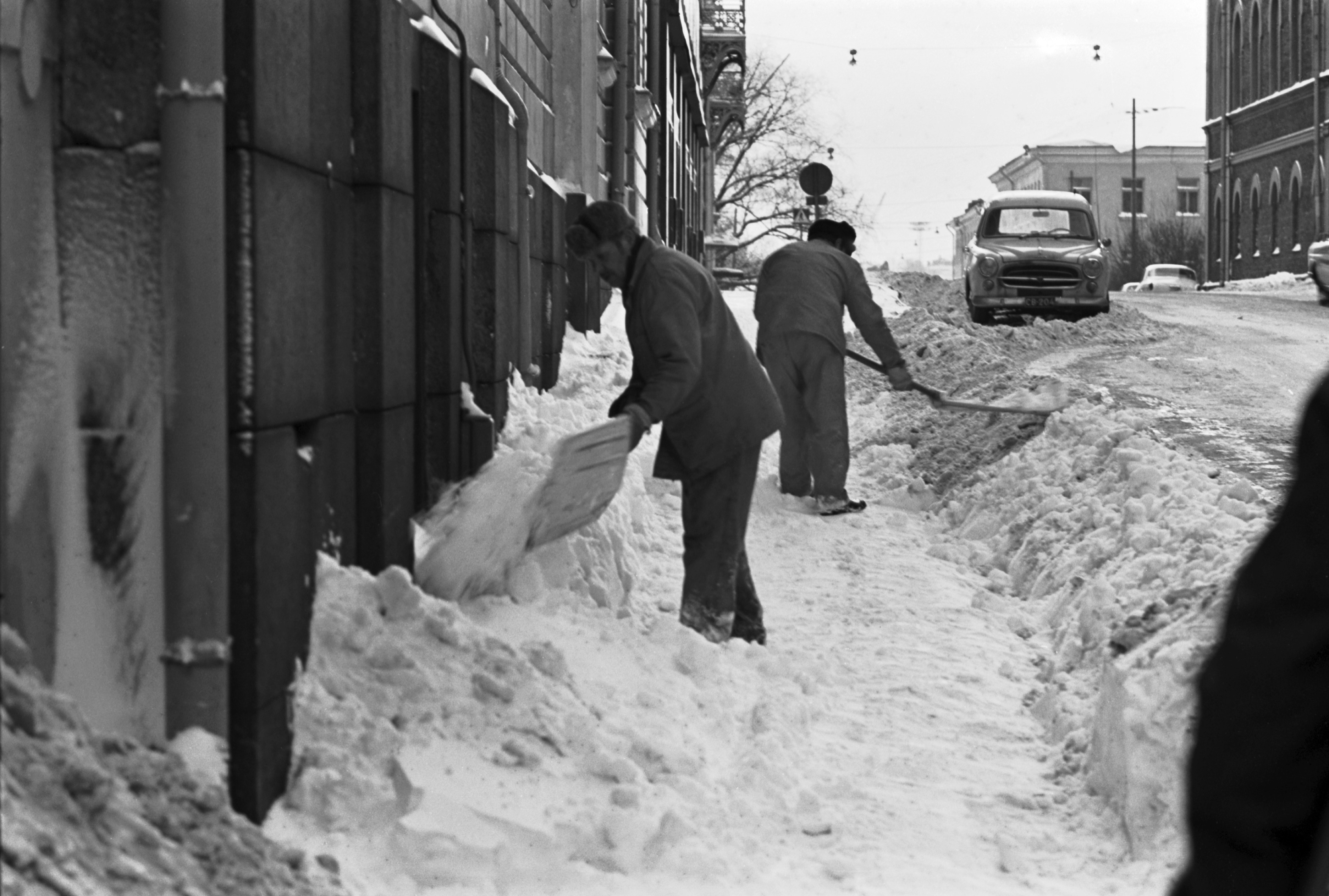 Mariankatu 11. Miehiä lapioimassa lunta Mariankadulla Ritarihuoneen kulmilla.