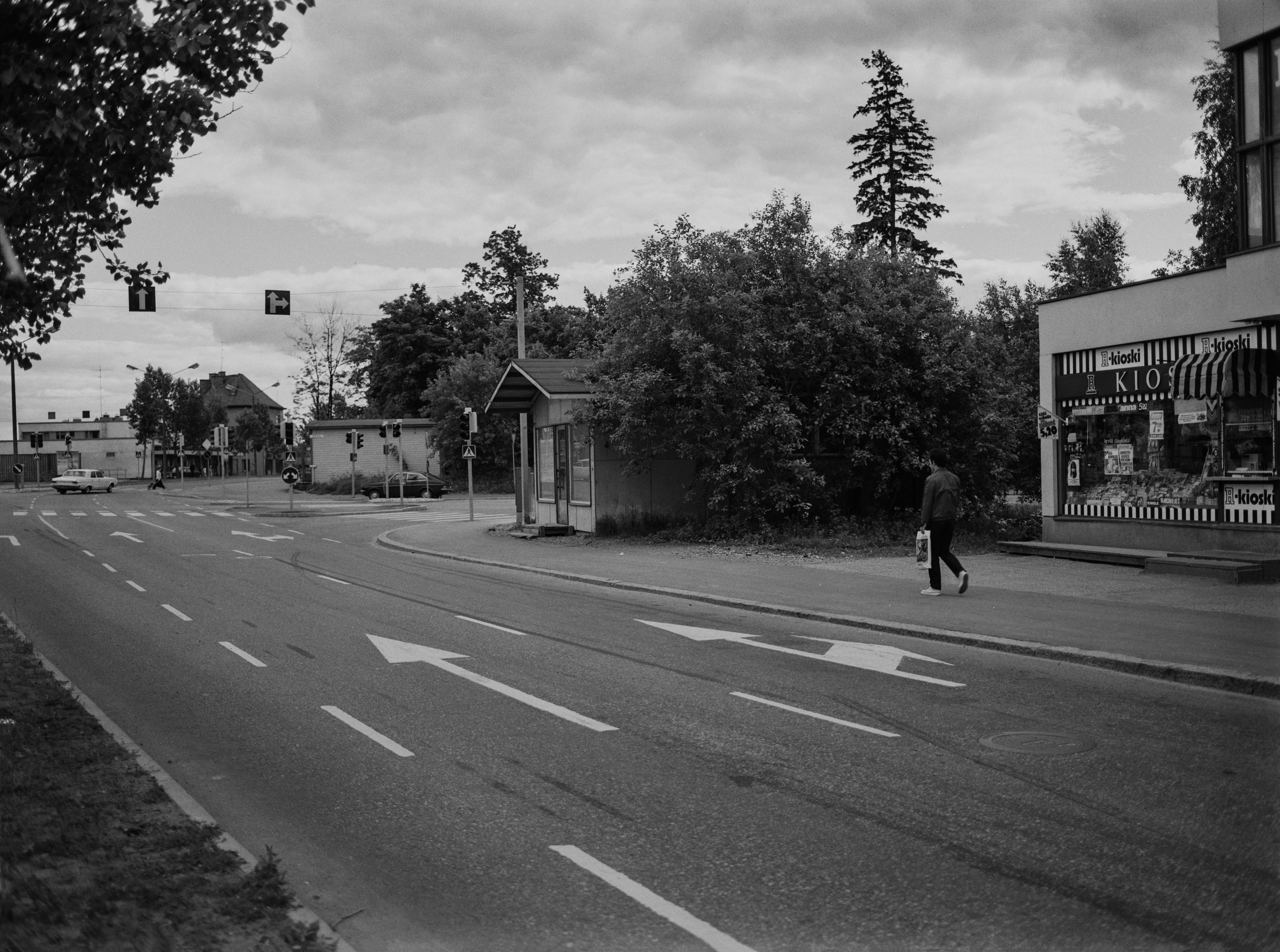 Kirkonkyläntie Ylä-Malmilla. Oikealla numerot 12, 10 sekä 8 ja vasemmalla valkoisen auton ja liikennevalojen jälkeen numerot 5 ja 3. Risteyksestäm oikealle alkaa Markkinatie.