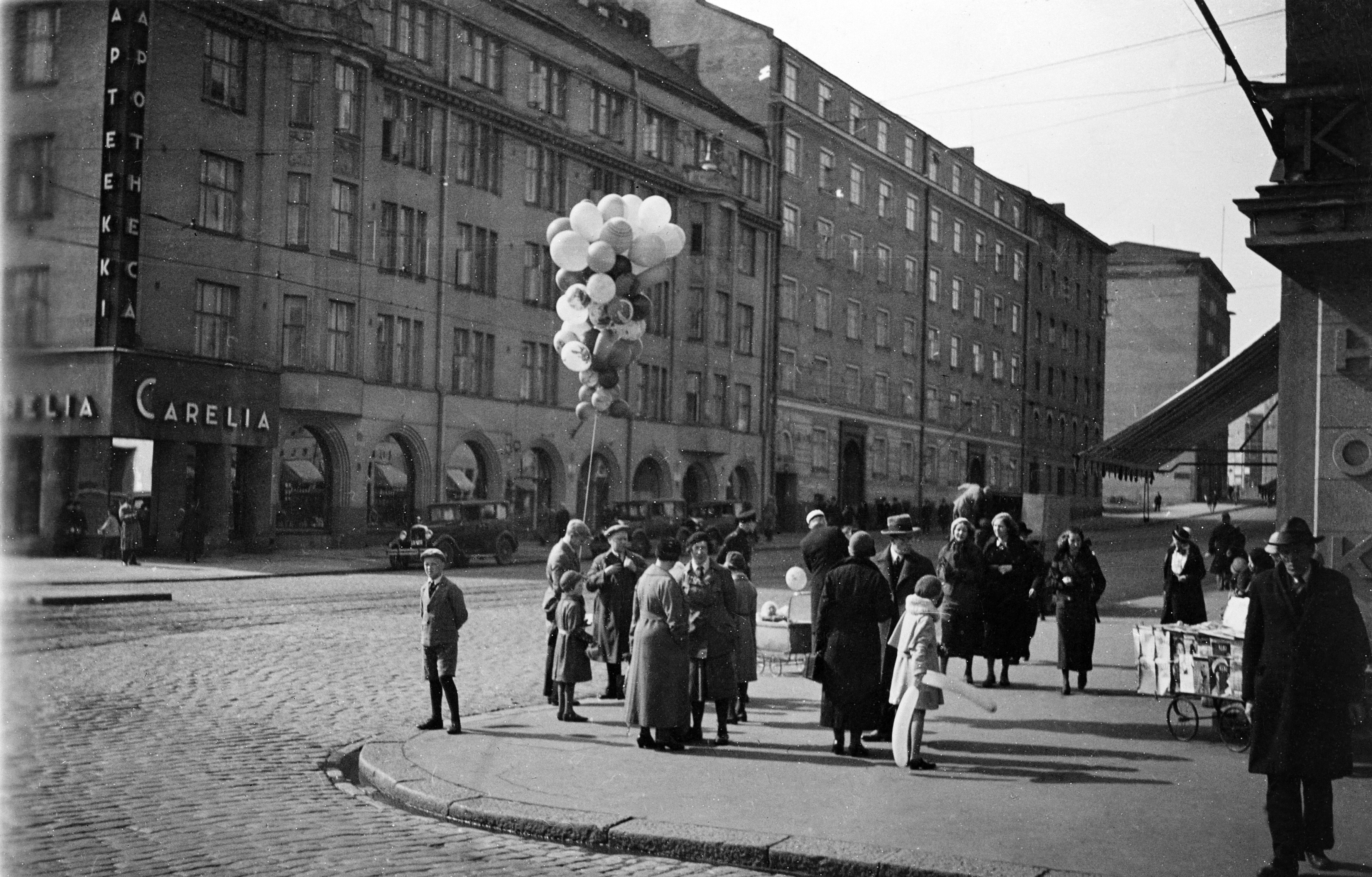 Ilmapallojen myyntiä vappuna 1934 HOK:n kulmassa, Turuntie (= Mannerheimintie 58) -Runeberginkatu 60. Kuvattu Turuntieltä.