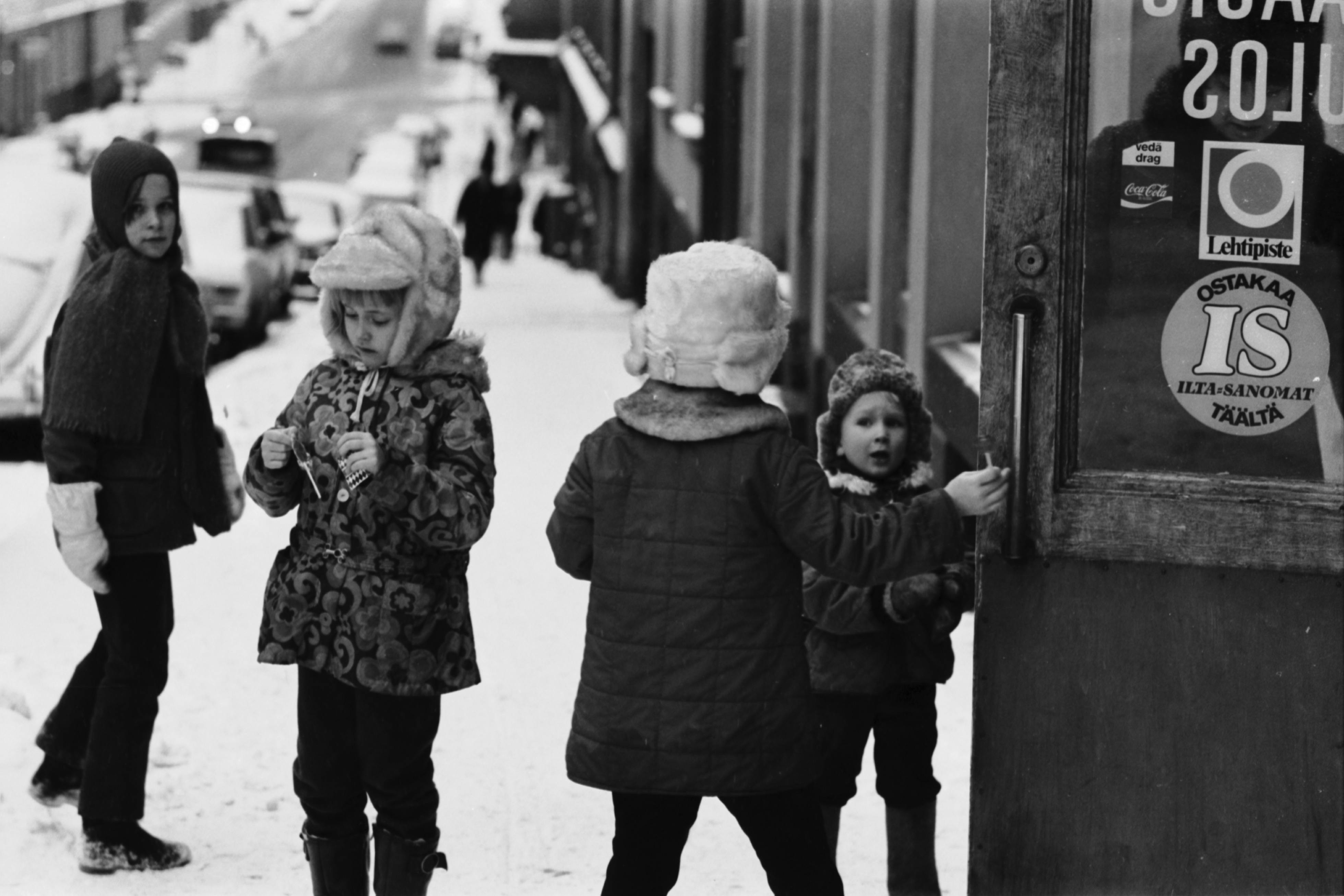 Kruununhaka, Mariankatu 18. Lapsia kivijalkamyymälän ovella Mariankadulla Vironkadun kulmassa. Näkymä etelään, Rauhankadun suuntaan.