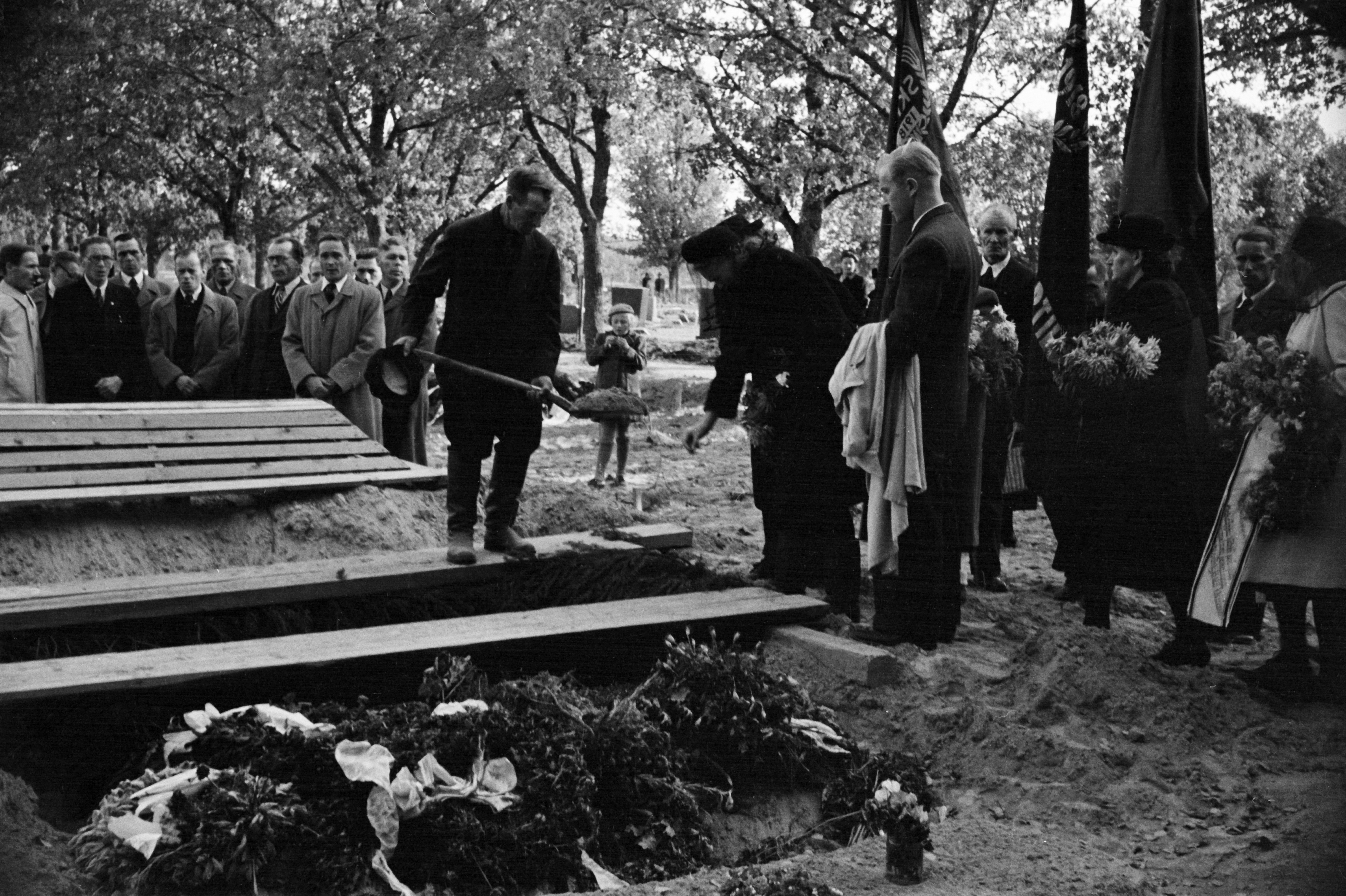 Pohjoinen hautausmaa (= Malmin hautausmaa), Jeremias Havian hautajaiset. Suruhuntuinen nainen heittää hiekkaa arkulle, vasemmalla hautausmaan vahtimestari. Haudan äärellä mm. Entiset Punakaartilaiset ry:n ja Suomen Kommunistisen Puolueen (SKP) liput.