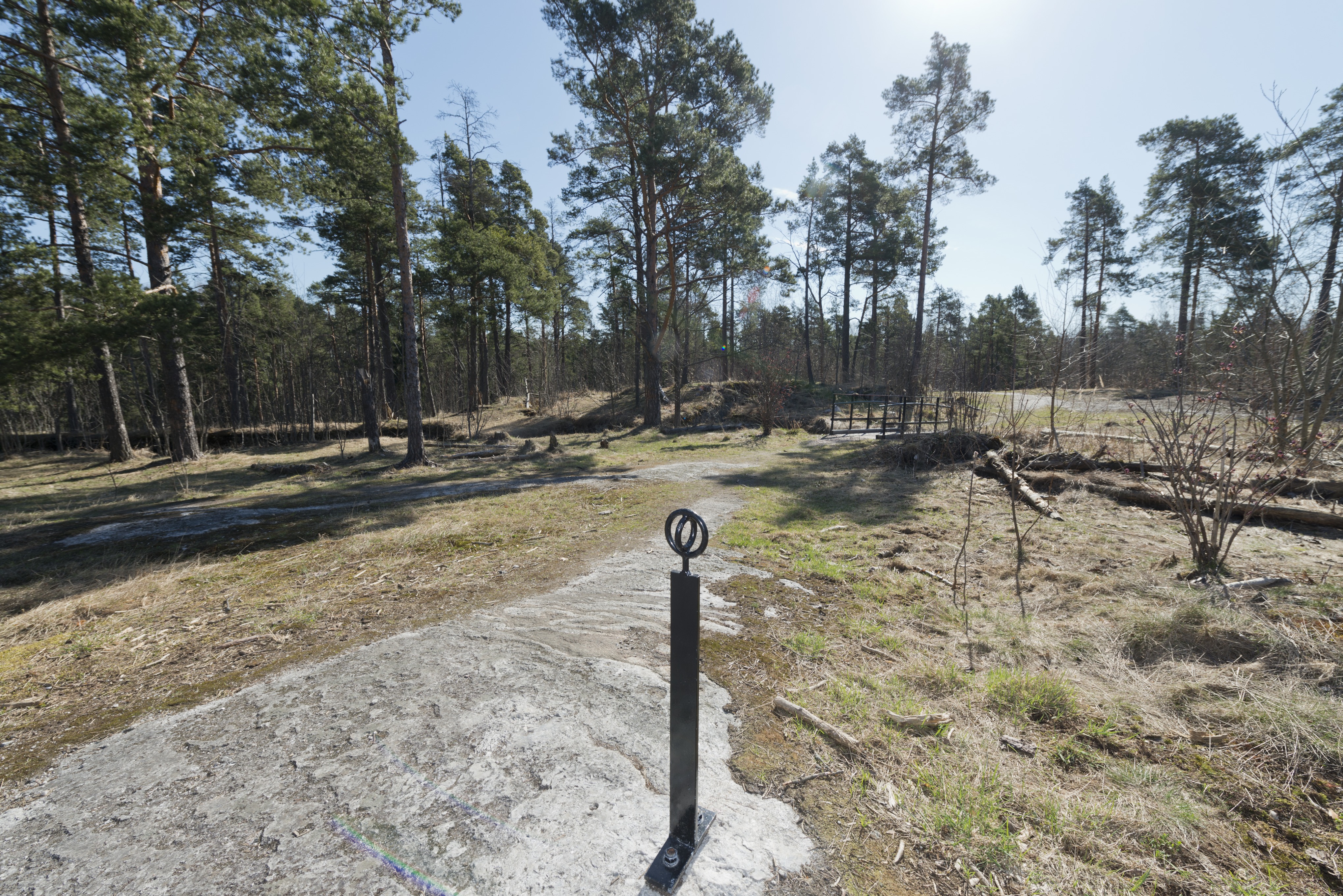 Länsimäki. Ensimmäisen maailmansodan aikainen maalinnoitus, puolustusasema II:7 Länsimäessä, Vantaalla. Kuvassa on aseman ympäristöä. Taustalla on haudan yli kulkeva silta aseman keskiosista. Etualalla on aseman läpi vievää polkua merkitsevä metallinen paalu, joka helpottaa vierailijoiden suunnistusta alueella. Kuvaussuuntana pohjoinen.