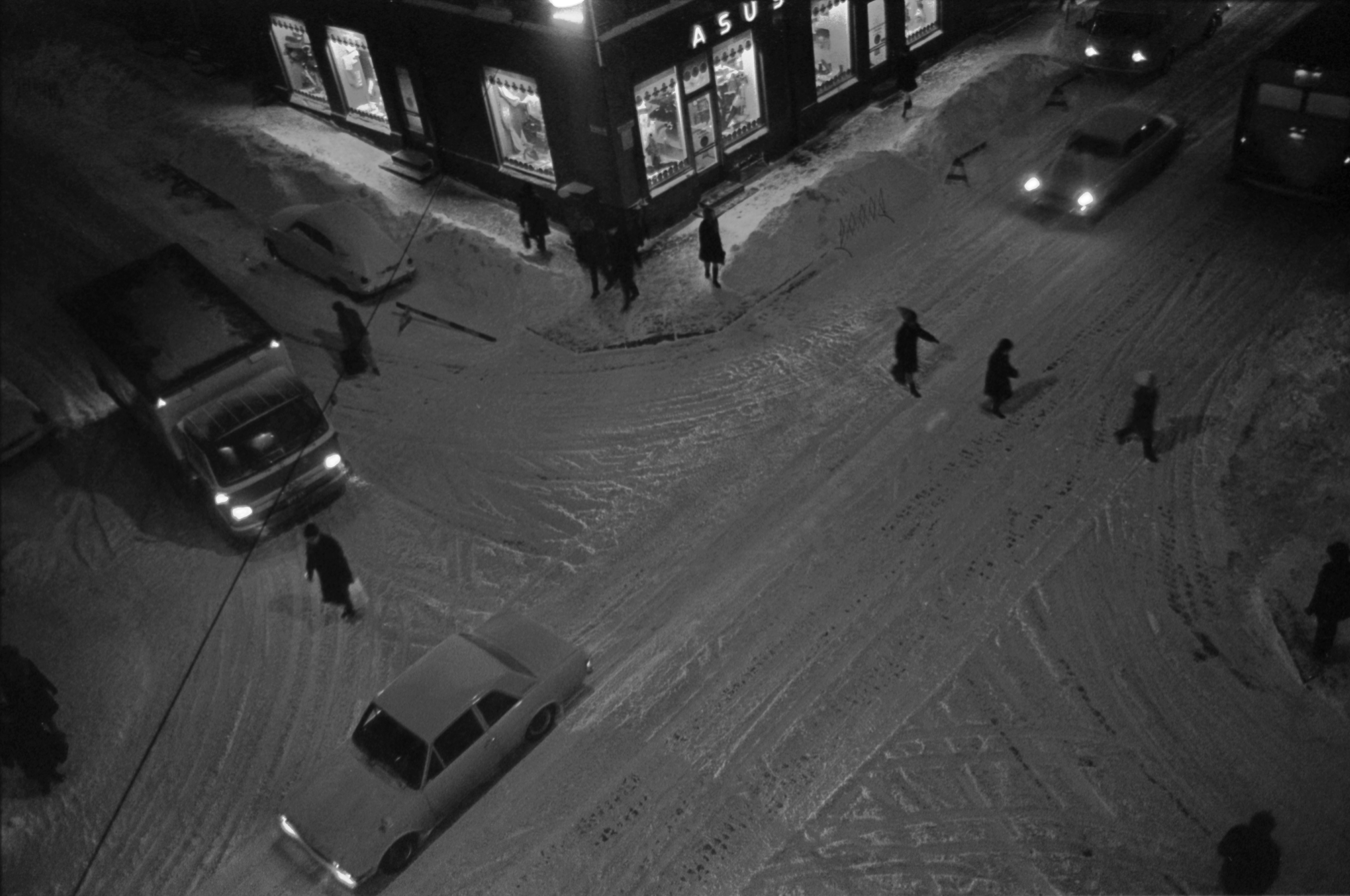 Liisankatu 6. Meritullinkatu 24. Jalankulkijoita ja autoja talvi-iltana lumisen Liisankadun ja Meritullinkadun risteyksessä. Kuvattu Liisankatu 7:n neljännen kerroksen ikkunasta.