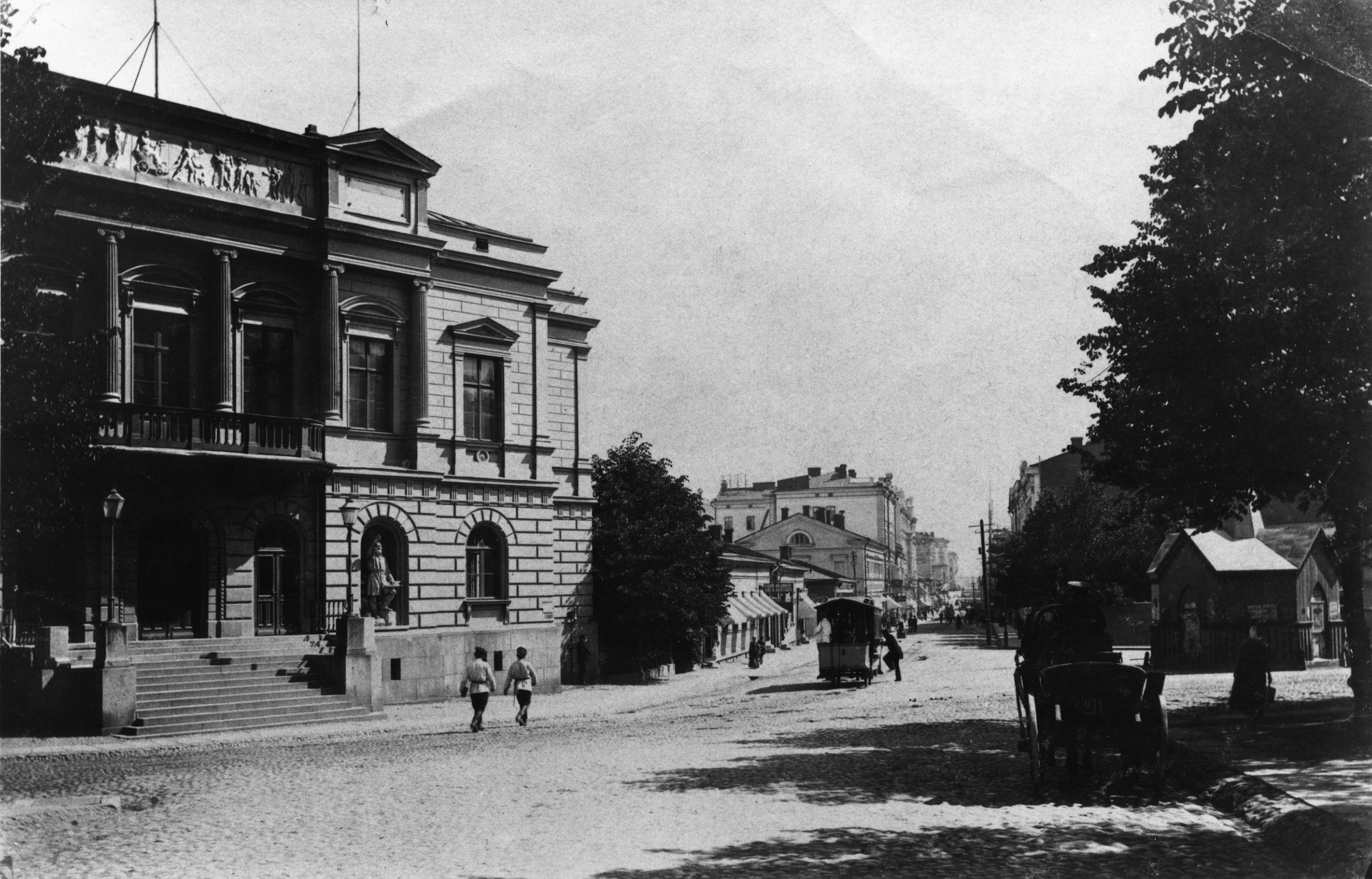 Aleksanterinkatu 23, 19, 17. Vasemmalla Vanha ylioppilastalo, Aleksanterinkatu 23, oikealla kaivo.