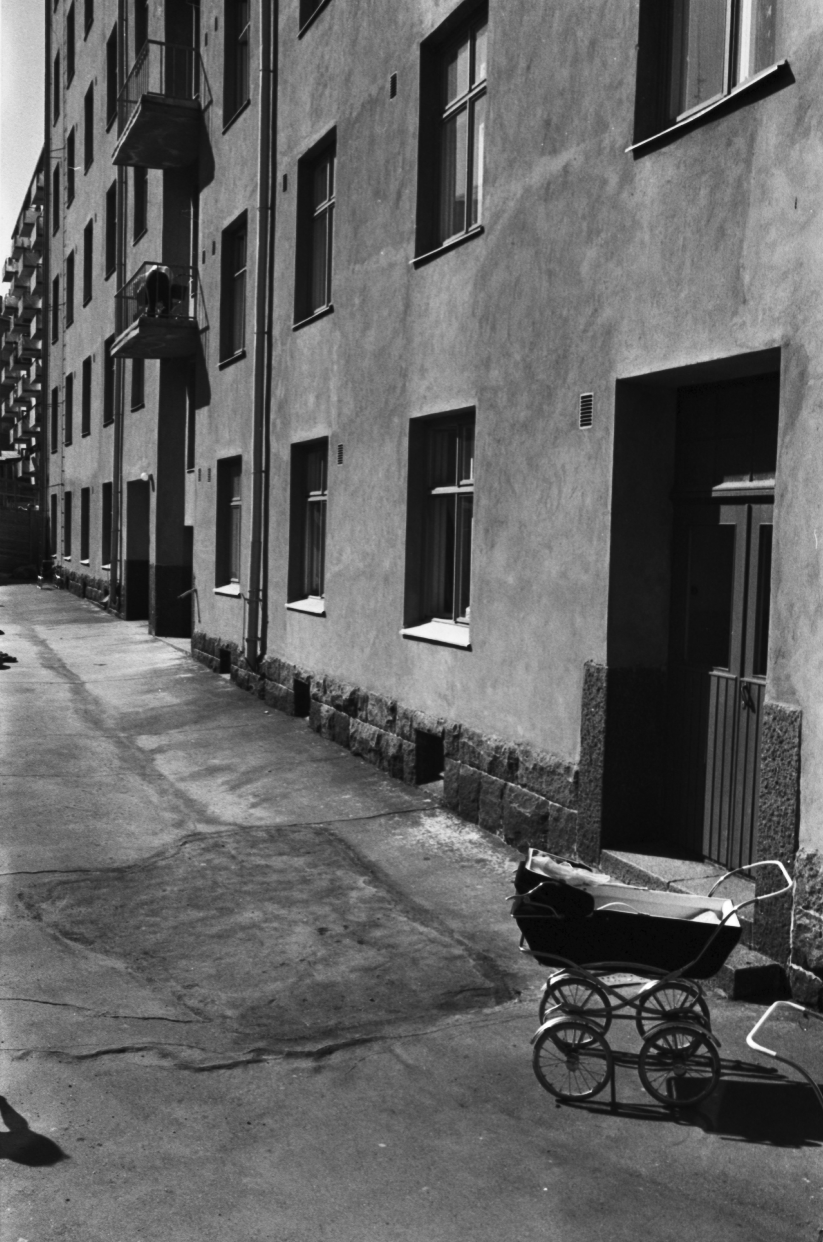 Alppikatu 15. Näkymä Alppikatu 15:n kerrostalon aurinkoiselta pihalta lännen suuntaan. Etualalla lastenvaunut.