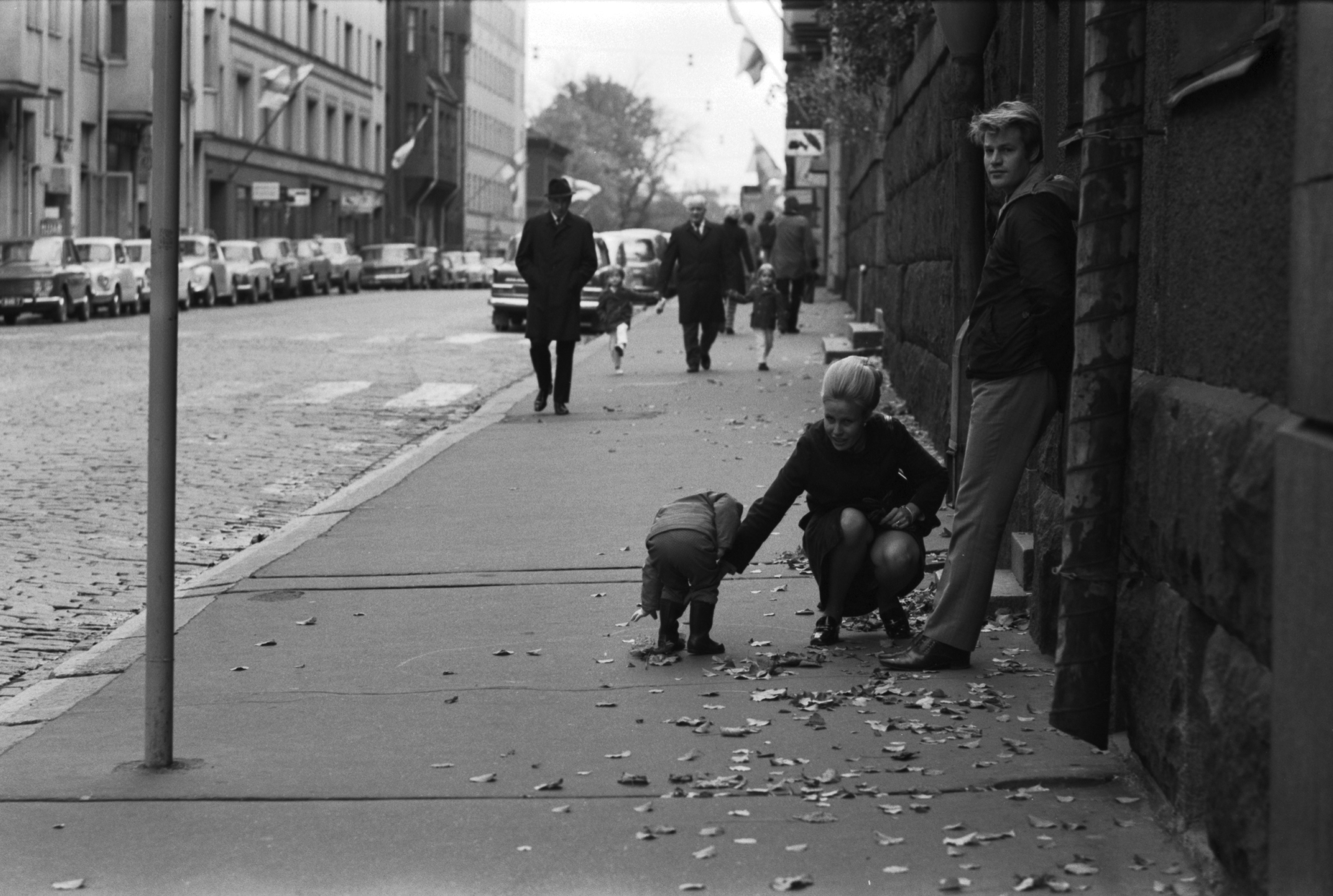 Kruununhaka, Liisankatu. Pieni lapsi, nainen ja mies bussipysäkillä Liisankatu 11:n kohdalla, taustalla jalankulkijoita.