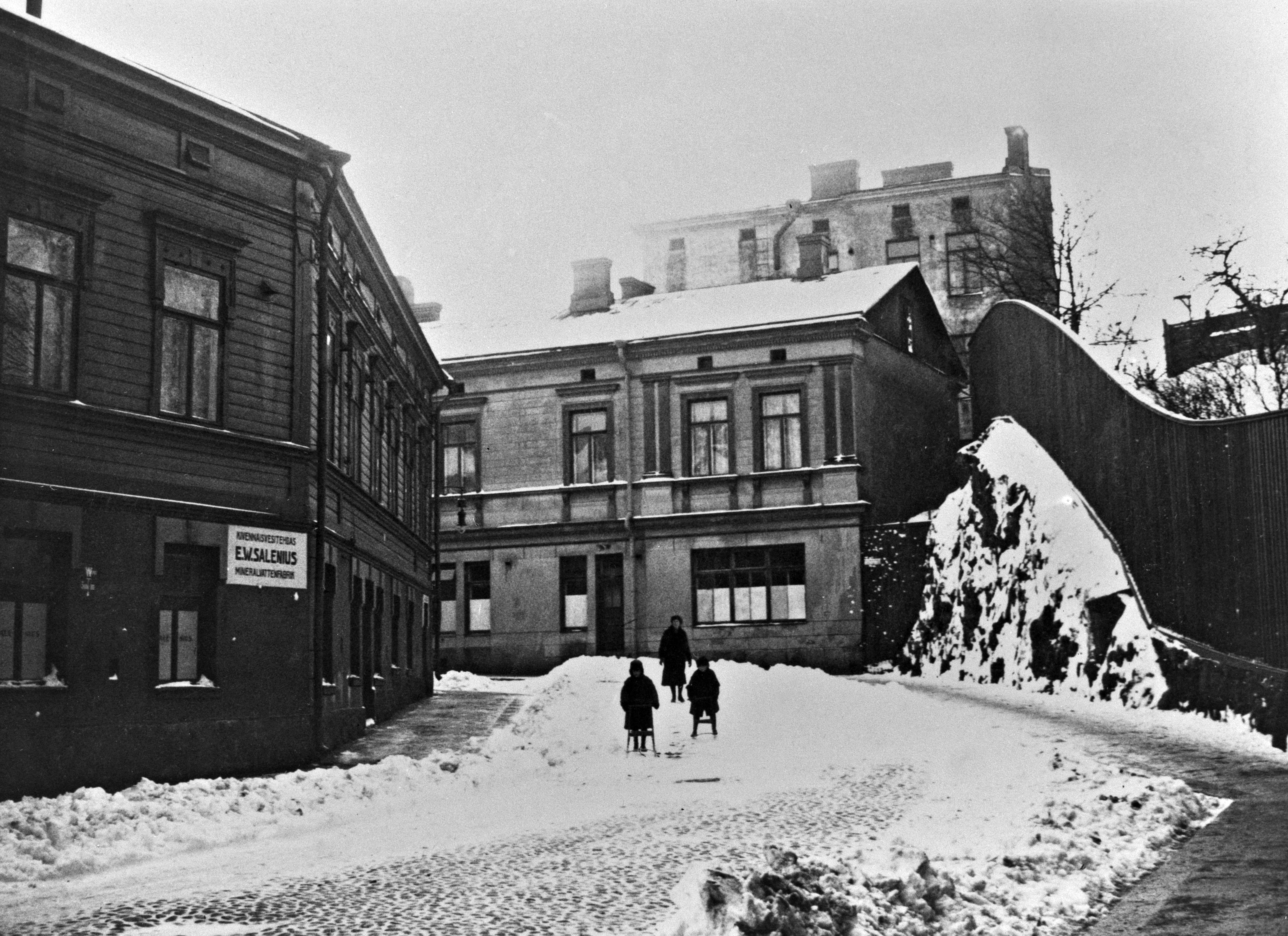 Iso Roobertinkadun loppupää. Käännöksestä alkaa Kivenhakkaajankatu. Vasemmalla kulmatalo E.W.Saleniuksen kivennäisvesitehtaan rakennus, Iso Roobertinkatu 52-Kivenhakkaajankatu 3. Kadun toisella puolen Kivenhakkajankatu 4.
