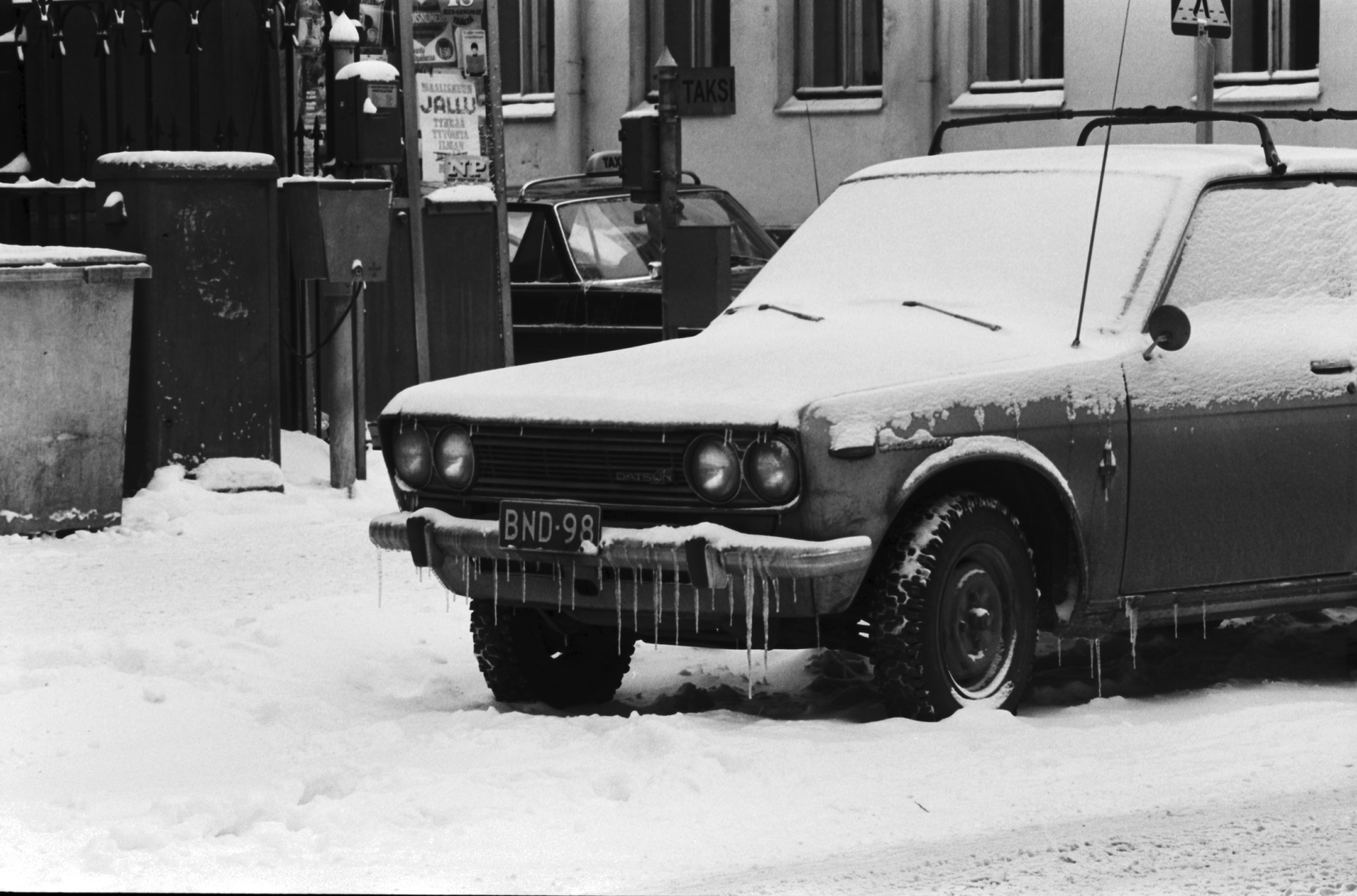 Kruununhaka, Liisankatu. Jääpuikkoja lumisen auton (Datsun 1300/1600 Bluebird) puskurissa Liisankadulla Mariankadun kulmassa.