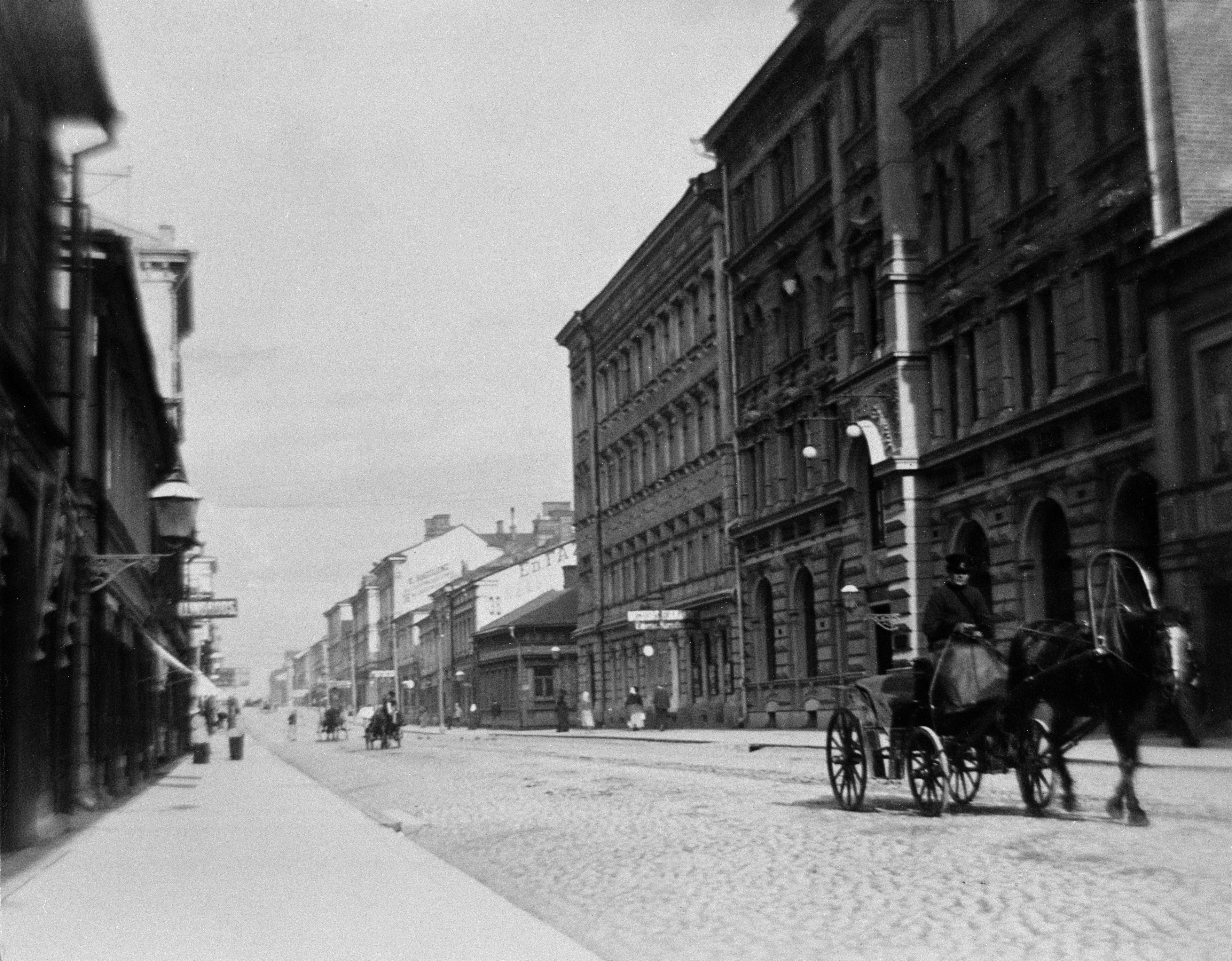 Aleksanterinkatua itäänpäin kuvattuna, oikealla Aleksanterinkatu 42, 40 ja 38, viimemainitut Kluuvikadun kulmataloja: Kluuvikatu 4 ja 3).