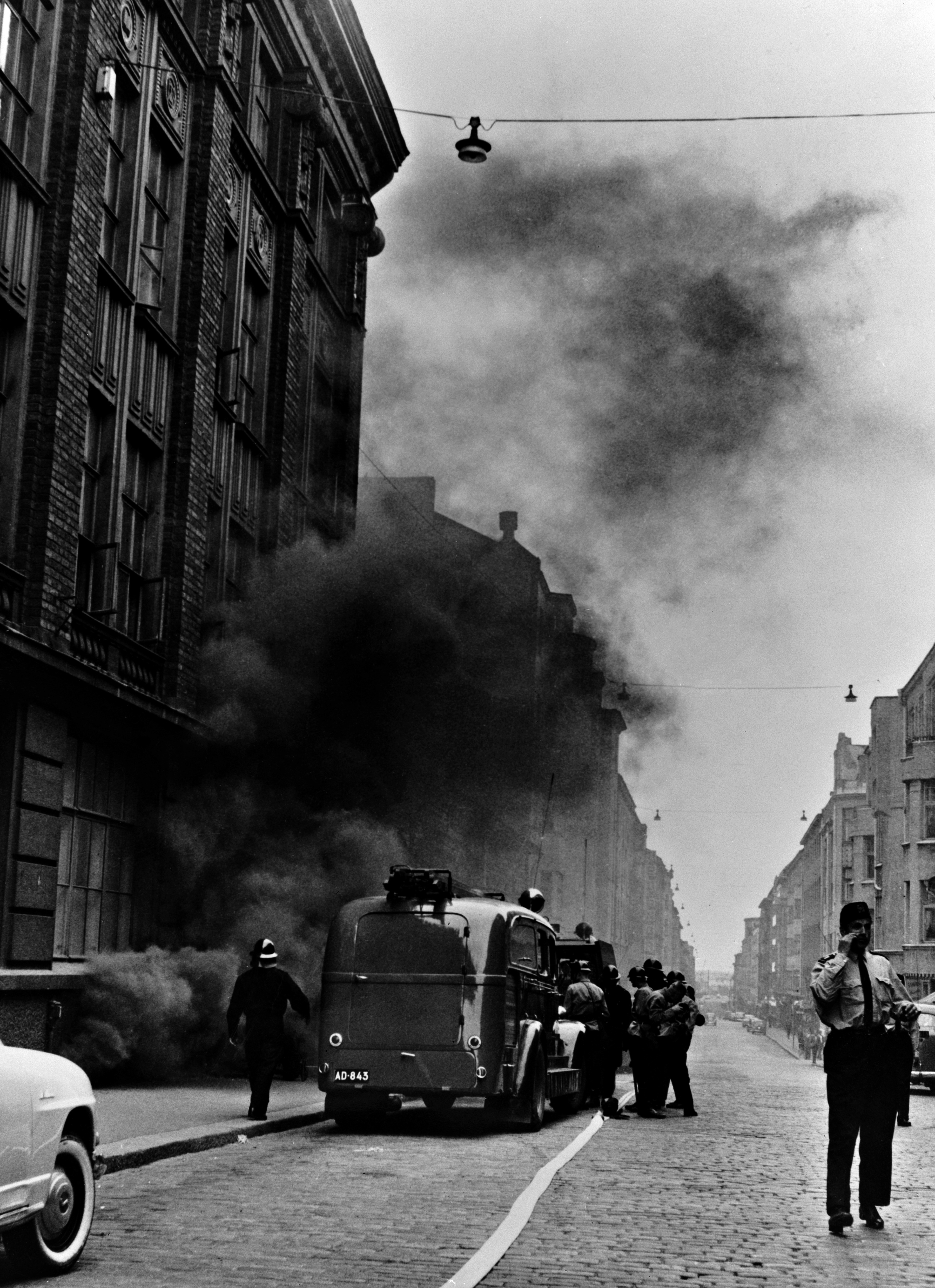 Oy Tilgmann Ab:n toimitalon palon sammutustyöt 12.7.1960. Kuva otettu palokunnan juuri saavuttua paikalle joitakin minuutteja ennen räjähdystä.