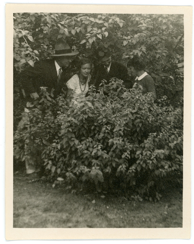 Johannes Vares sõpradega aias põõsaste vahel