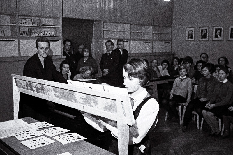 Tallinna Linna TSN Täitevkomitee haridusosakonna metoodilise kabineti muusikaõpetajate ainesektsiooni esimees, Tallinna 39. keskkooli muusikaõpetaja Koit Kirber (vasakult 1.) kooli muusikaklassis Tallinna lauluõpetajate omakonstrueeritud noodiõpetuse abivahendit- noodilotot demonstreerimas.