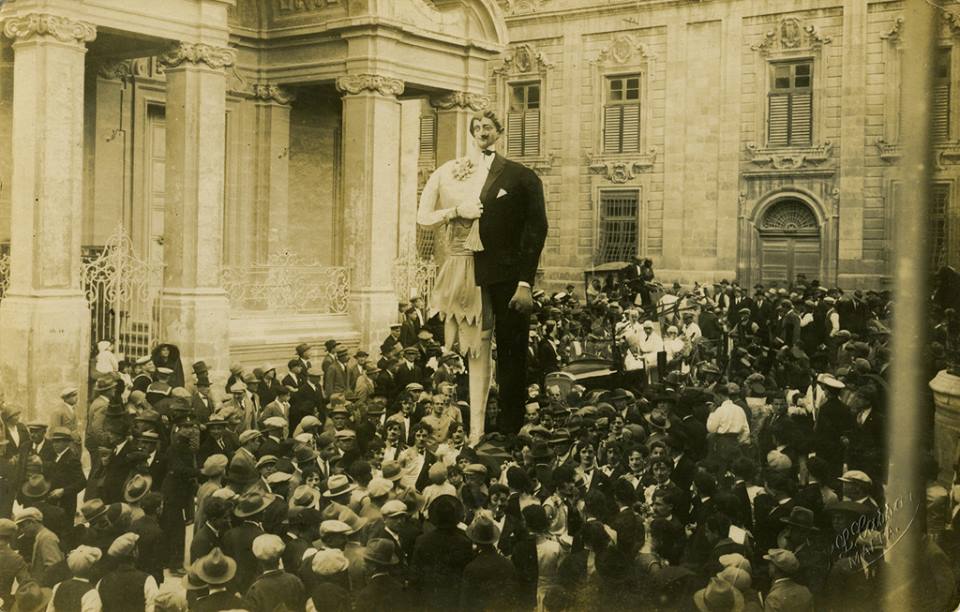 Carnival of Malta - S. L. Cassar (1855-1928) - "1921 was the year of (very) limited self rule or self government granted by the British colonial powers. The half man half woman theme with the half mustache translates to "half shaved" in Maltese. This has the same meaning as "half baked" or "middle of nowhere" in the English language, maybe a commentary on the limited self government and its effectiveness in actual reality." (Frank Lea-Ellis)