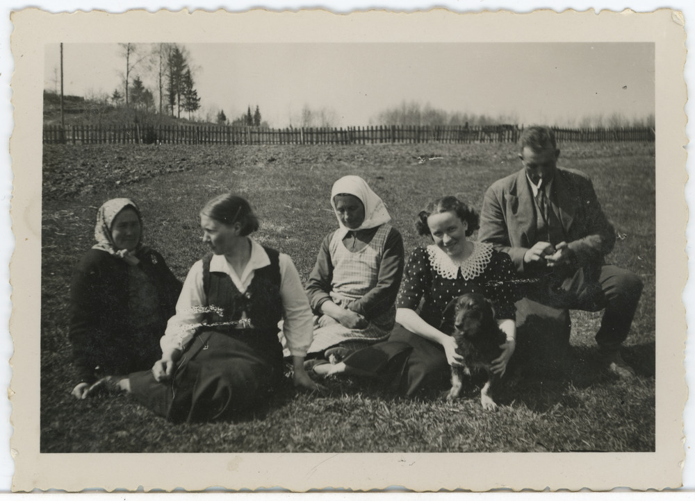 Grupp inimesi maastikul istumas, paremalt teine Salme Maling (Maimre, Ümarik) koos koeraga