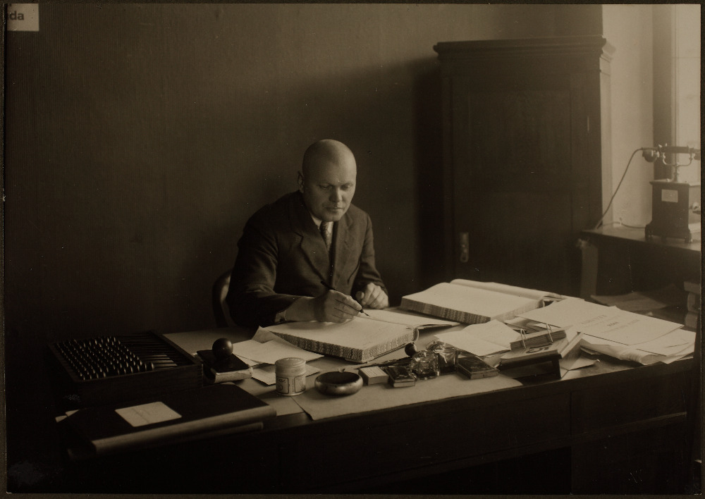 Pearaamatupidaja M. Einberg töölaua taga istumas ja kirjutamas