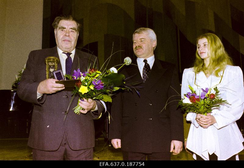 Eesti Vabariigi 80. aastapäeva puhul Pärnumaa vapimärgi omanikuks saanud  spordiveteran Aksel Randmer (paremal). Õnnitlejad Pärnu linnapea Vello Järvesalu ja Pärnu miss.