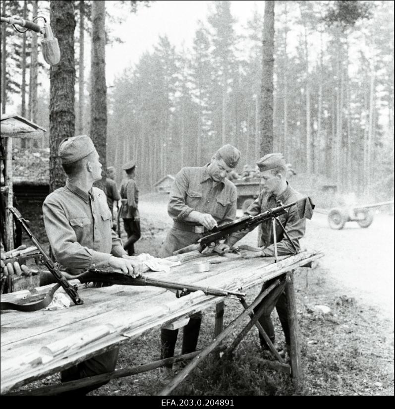 Stseen Tallinnfilmi mängufilmist "Inimesed sõdurisinelis". Relvadega tegelevad (vasakult) Veski (Arvi Hallik), Tääger (Heino Raudsik) ja Viies (Kenno Oja).