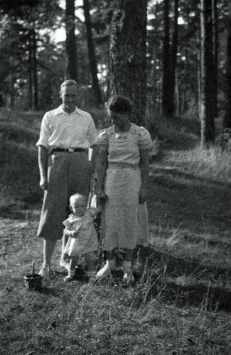 Mees, naine ja väike laps männimetsas.