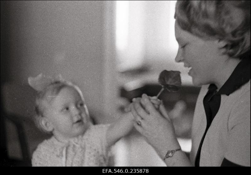 Väike tüdruk ulatab emale lille. (H.Leppikson "Lill emale")