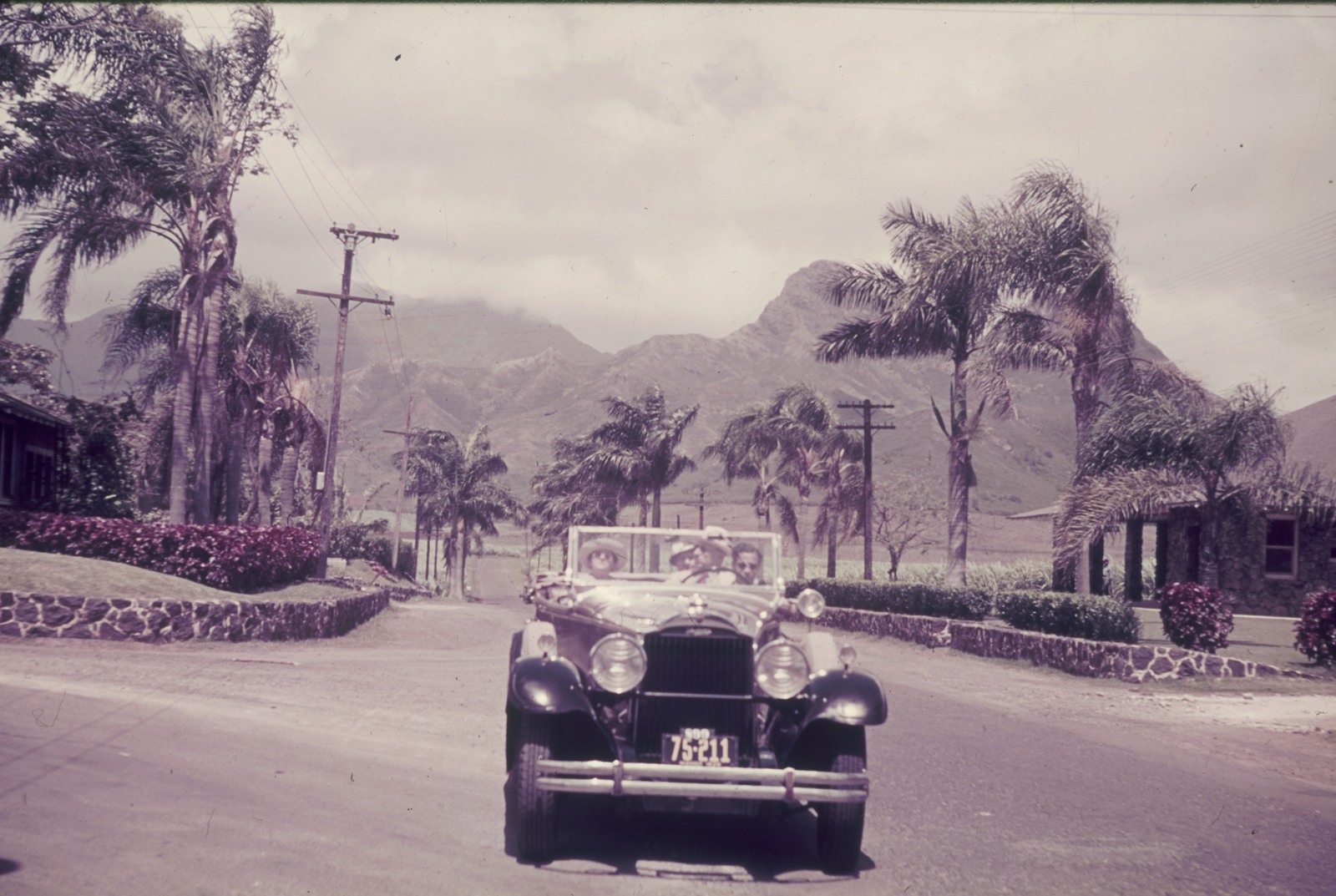 Reisefotos. Automobil mit Linkssteuerung (Kfz-Nr. S 99 75-211) während einer Ortsdurchfahrt. Blick zu einer Gebirgskette (wahrscheinlich in der spanischen oder französischen Karibik)