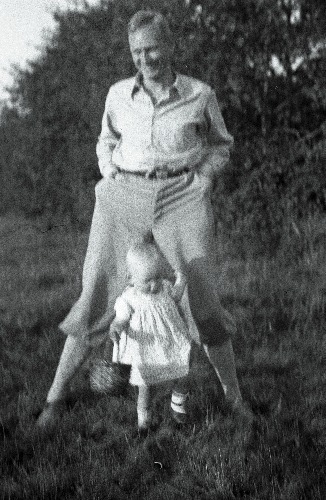 Georg von Krusenstiern lapsega. Isa seismas jalad harkis, laps tema jalgadest kinni hoidmas.