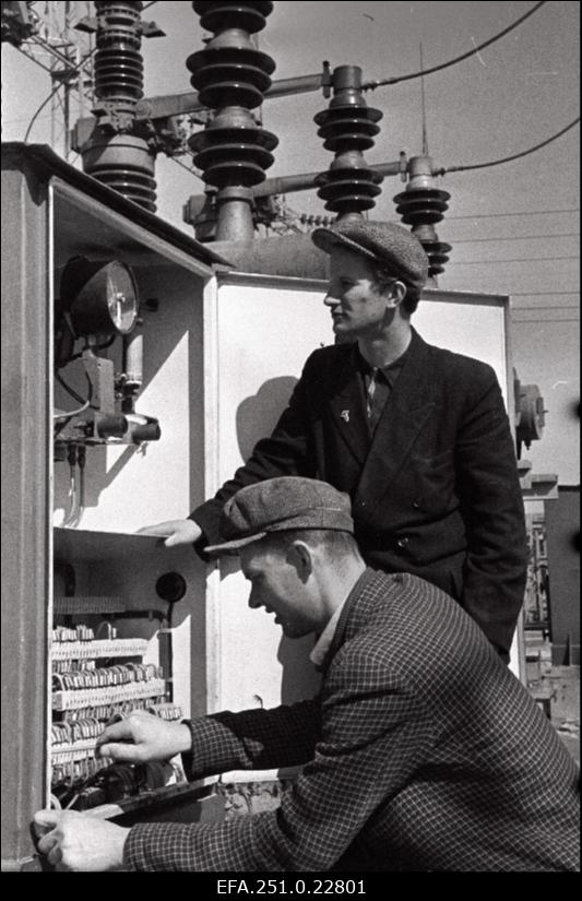 Eesti Soojuselektrijaama elektrilaboratooriumi insener, kommunistlik noor Ants Puugas ja elektritsehhi vahetusmeister Leo Taimsoo korrastavad lahtises alajaamas võimsuslüliti sekundaarahelat.