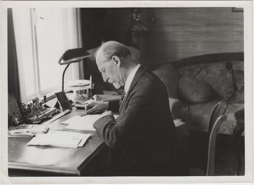 Jaan Tõnisson kirjutuslaua taga pabereid uurimas.