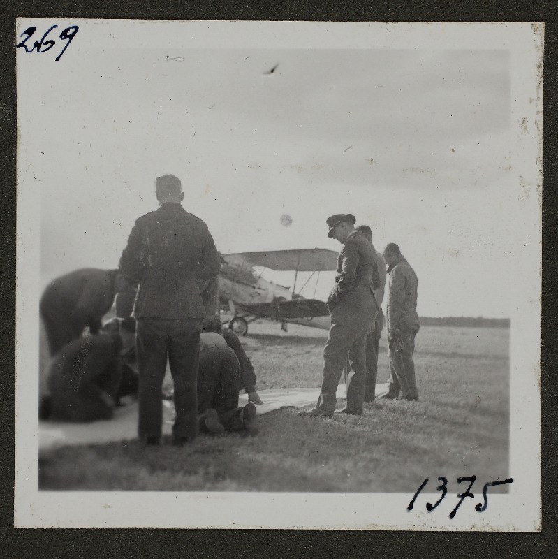 Grupp sõdureid [1. Lennuväedivisjonist?] põllul lennuki taustal