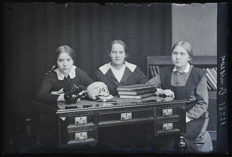 Grupp neiusid, vasakul Märtik, laual pealuu, (foto tellija Ormisson).