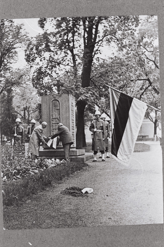 Eesti Akadeemilise Sõjaajaloo Seltsi liikmed ja 1943 - 1944.a. Soome jätkusõjast osavõtnud Eesti Vabatahtlike külaskäigul Soome asetatakse pärg Eesti Vabadussõjast osavõtnud Soome vabatahtlike mälestussambale. Esiplaanil Eesti Akadeemilise Sõjaajaloo Seltsi lipp.