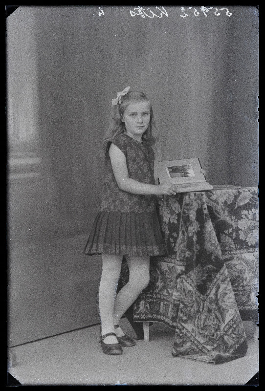 Tüdruk fotoalbumiga, (foto tellija Kits, Kaarli vald, Araku talu).