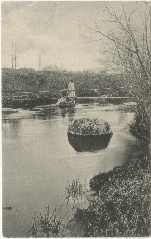 Esiplaanil veekogu ja kivi, taamal mees sillal