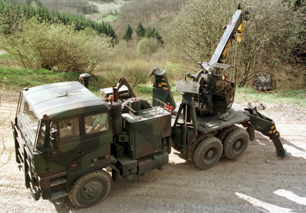 Een DAF YBZ 3300 DKX Ati 120 kN 6x6-takelauto, met twee uitgeschoven stempels voor meer stabiliteit, bergt een van de weg geraakte Land Rover.