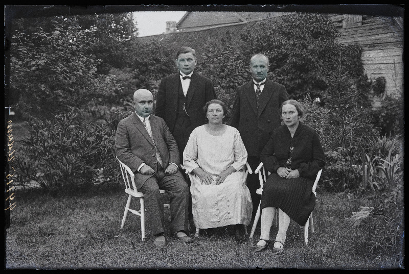 Grupp inimesi aias; vasakul istub Aleksander Udam, kõrval abikaasa Marie Udam, (foto tellija Udam).