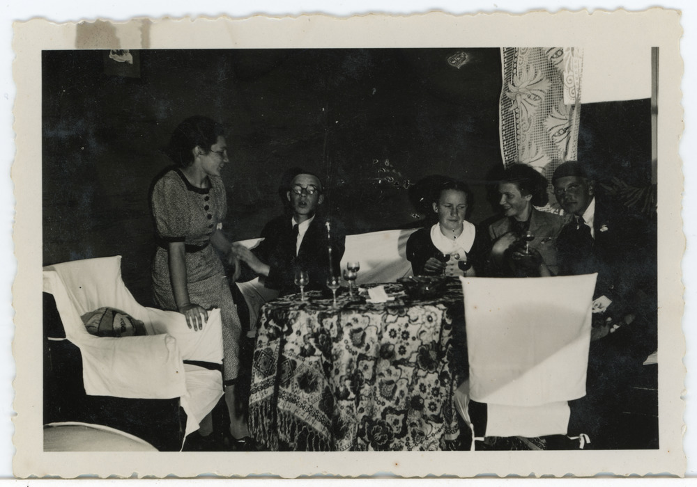 Grupp inimesi toas laua taga istumas, keskel Salme Maling (Maimre)