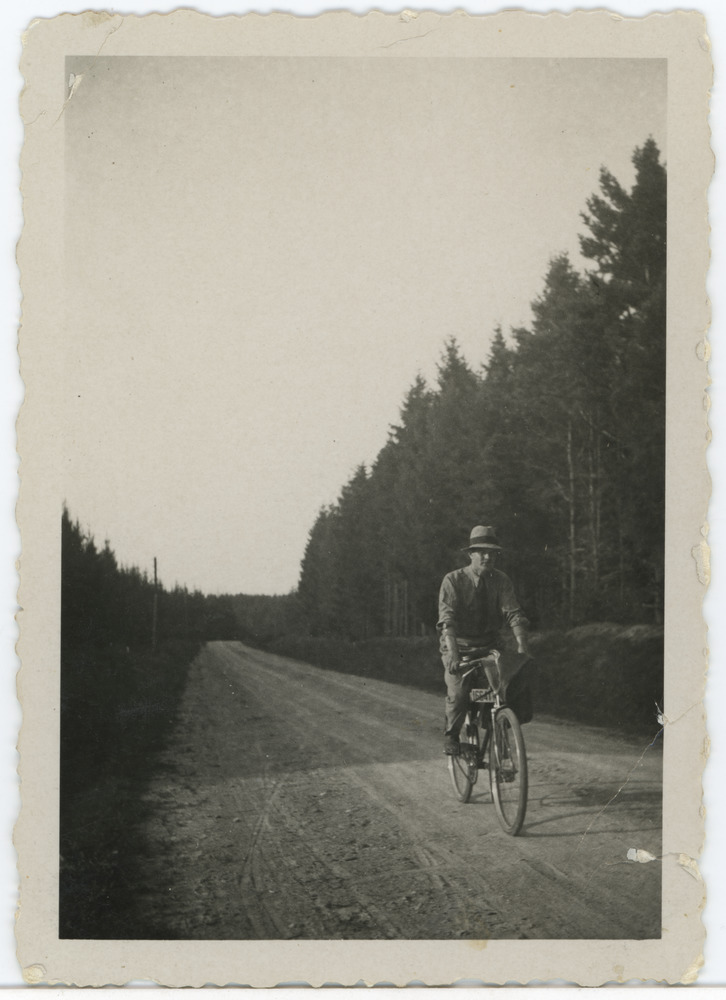 Noormees jalgrattaga metsavahelisel teel sõitmas